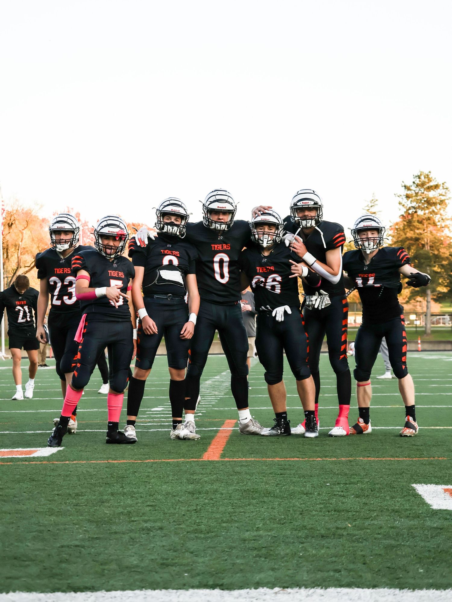 Group of football players in black Tigers uniforms pose together on field during autumn.