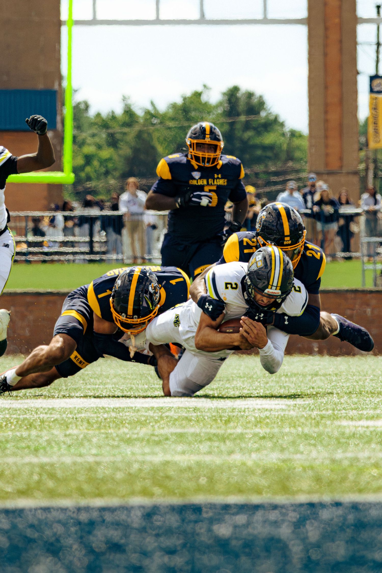 Football player dives horizontally to make a diving tackle during an intense game on the field.