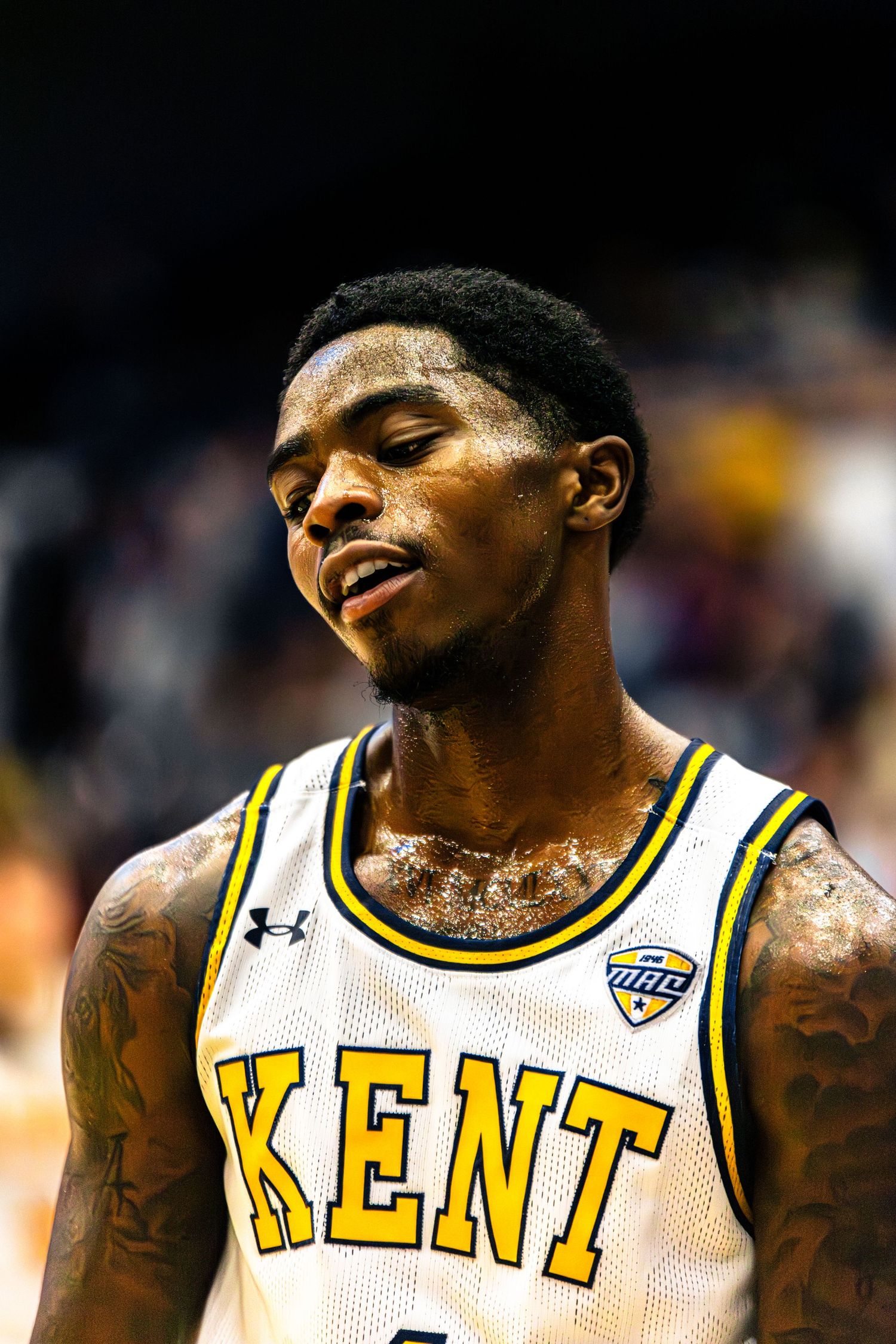 Basketball player in Kent State white jersey with Under Armour logo shows emotion during game.