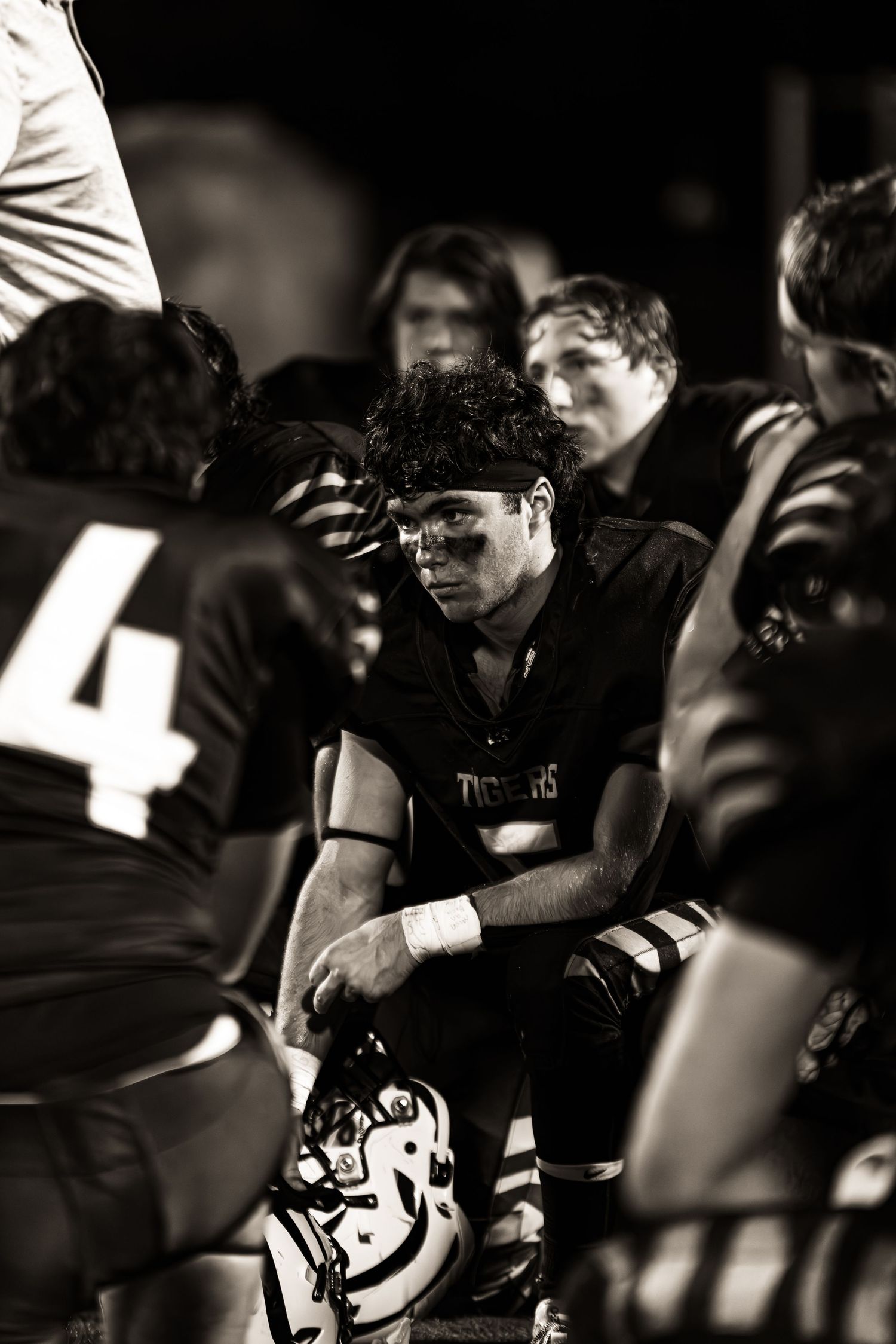 Black and white photo of football players on the sideline during a game.