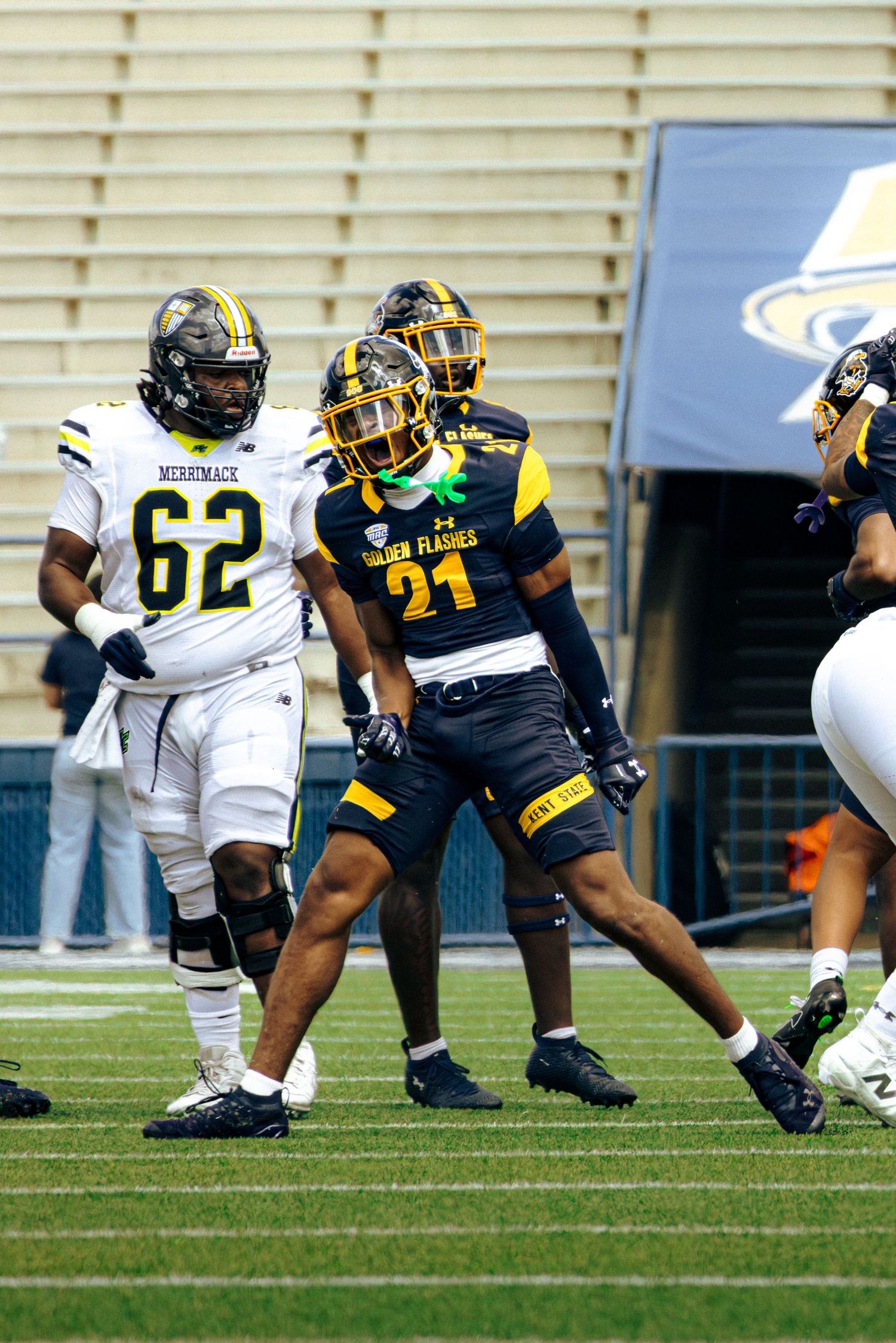 Football players in black and gold uniforms compete against opponents in white jerseys during a college game.