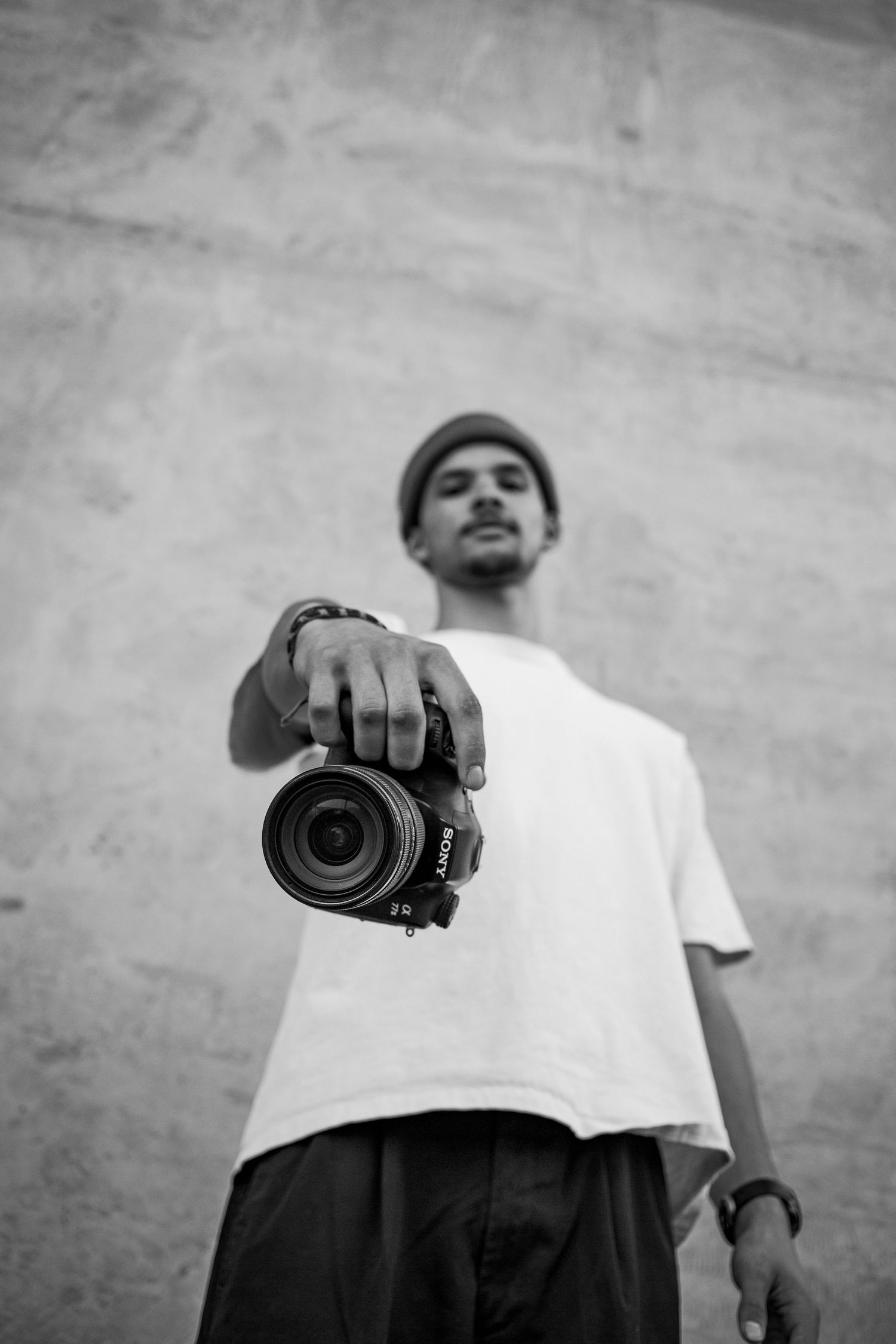 This black and white photo show a photographer showcasing his camera in a urban concrete setting located in Boise Idaho