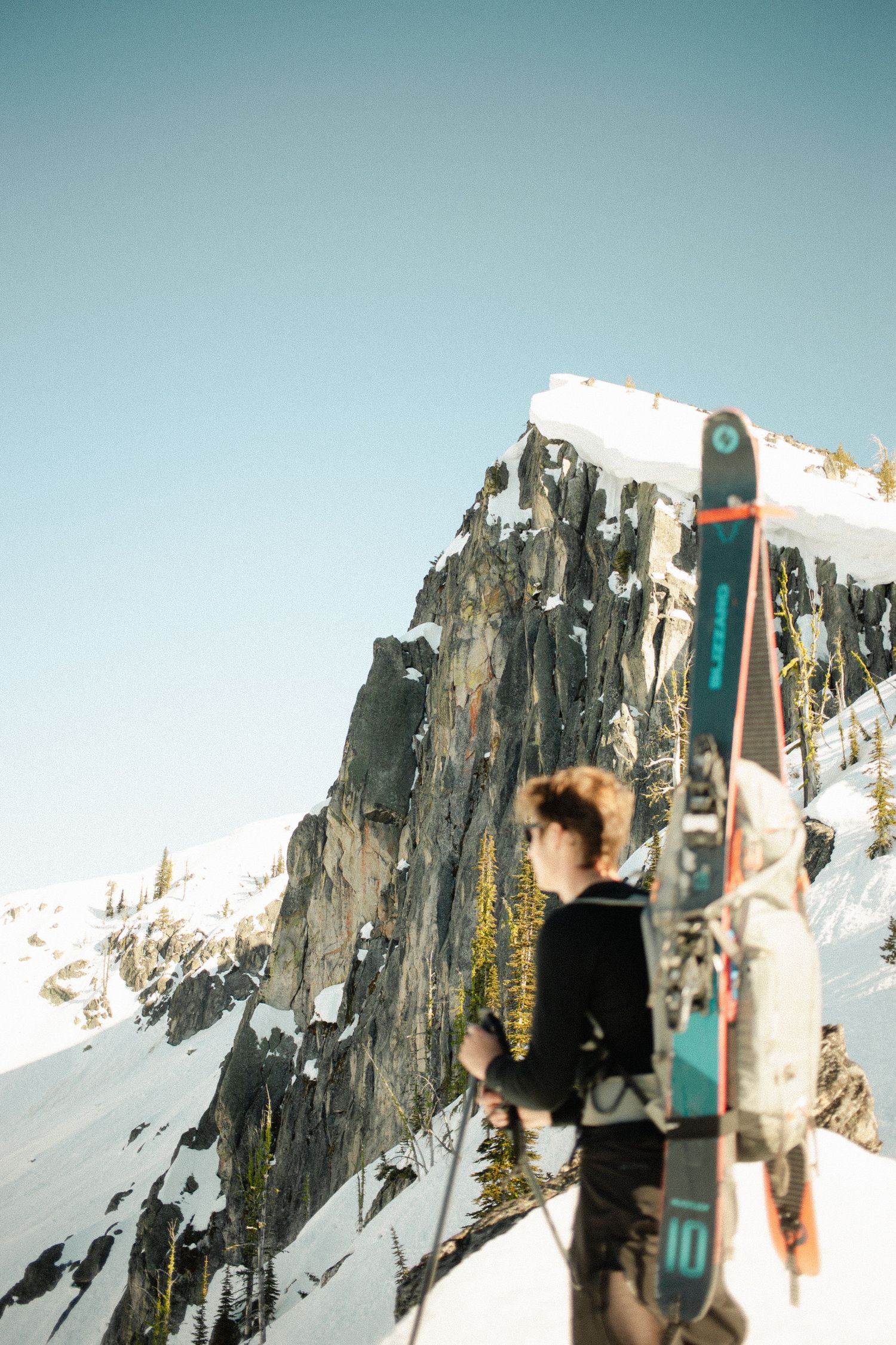 Back country skier stands infant of a looming mountain getting ready to reach the summit located in northern Idaho