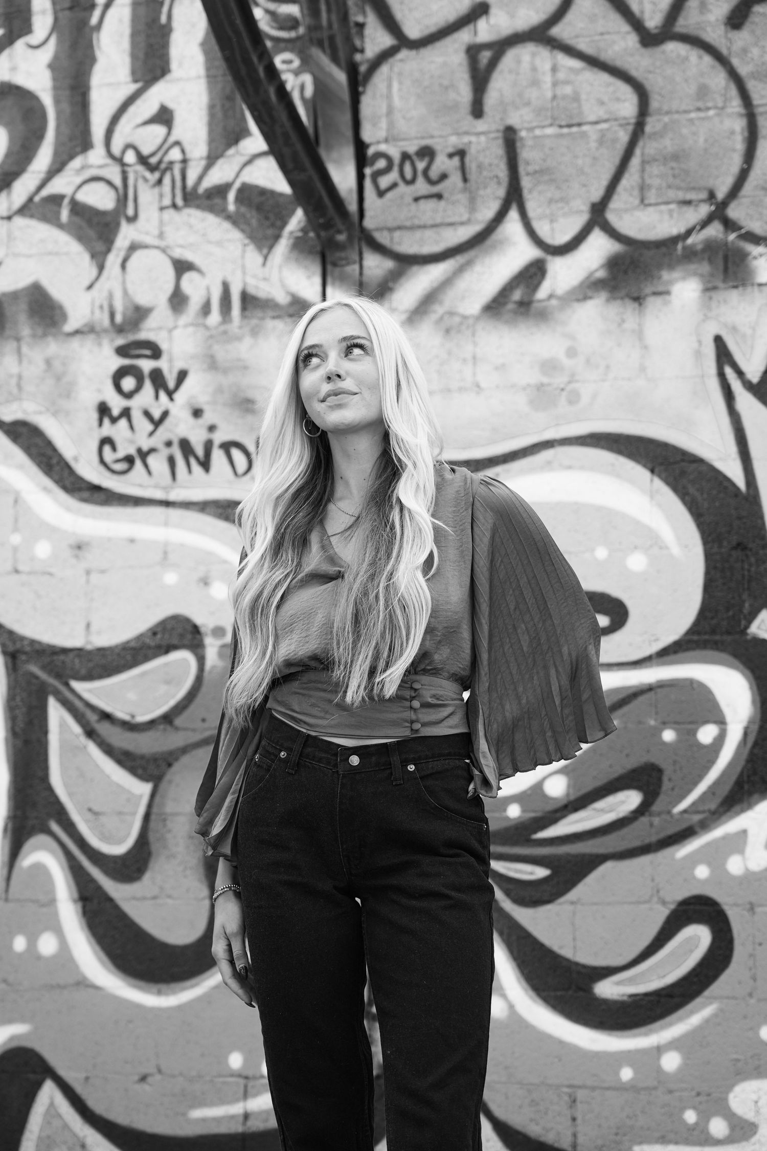 Black and white portrait against graffiti wall showcasing urban fashion and artistic expression.