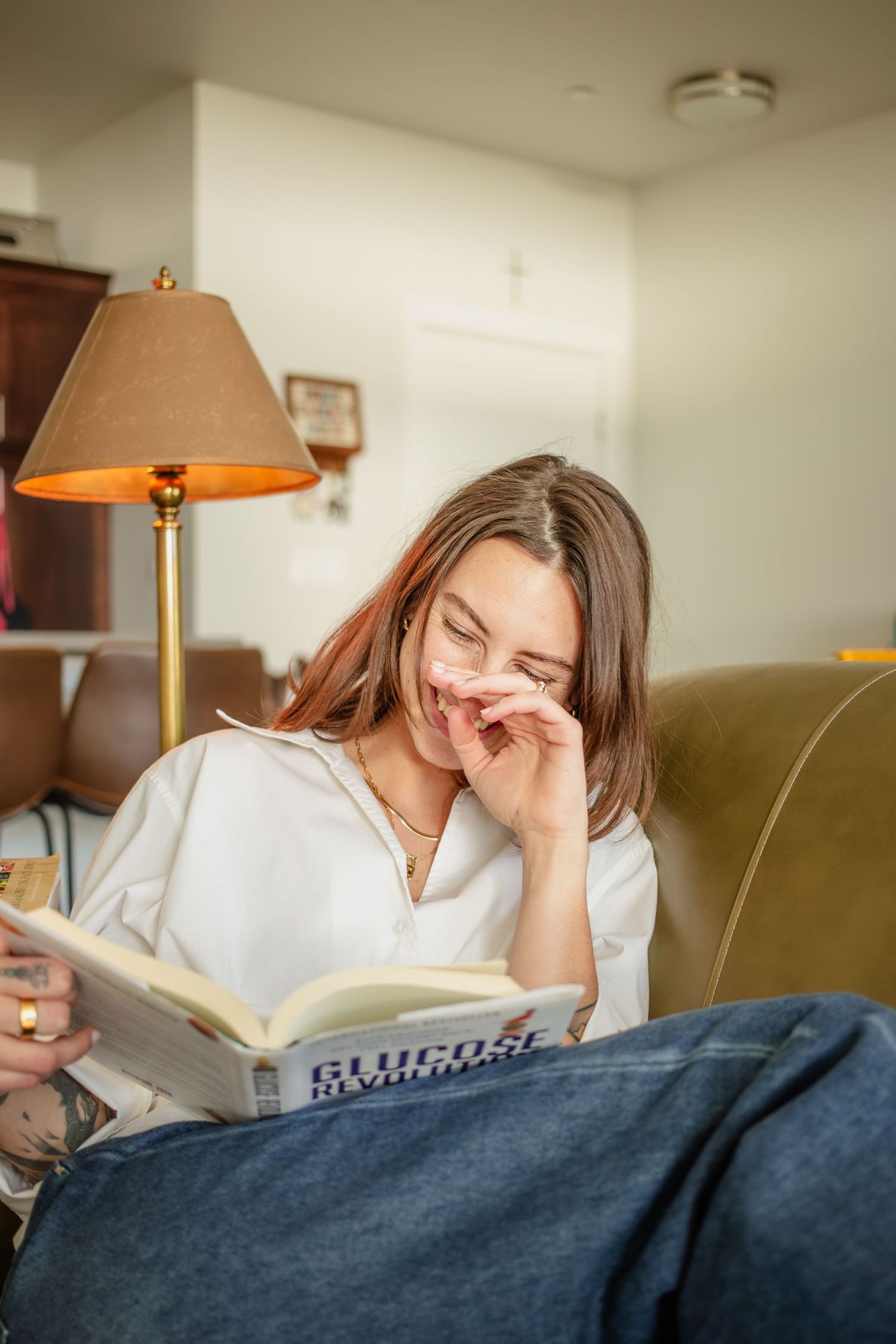 This warm image shows a girl as she reads a book on her couch as she poses for in home portraits taken by Stoked Media in Eagle Idaho