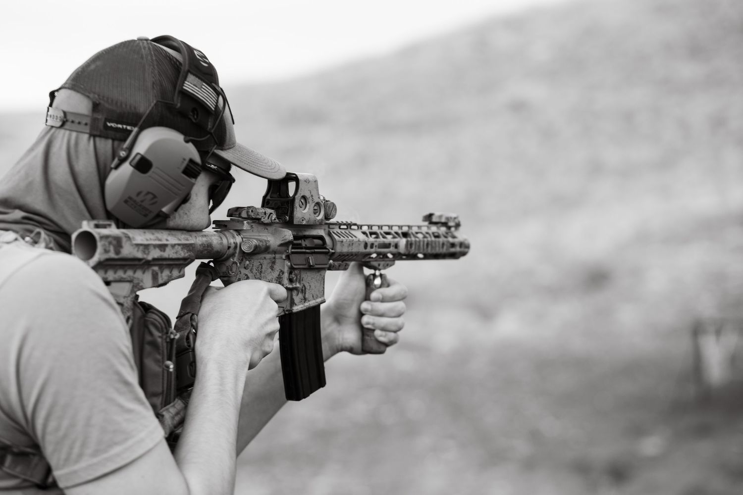 A person aims a rifle at an outdoor shooting range with tactical gear and equipment in the boise foot hills.