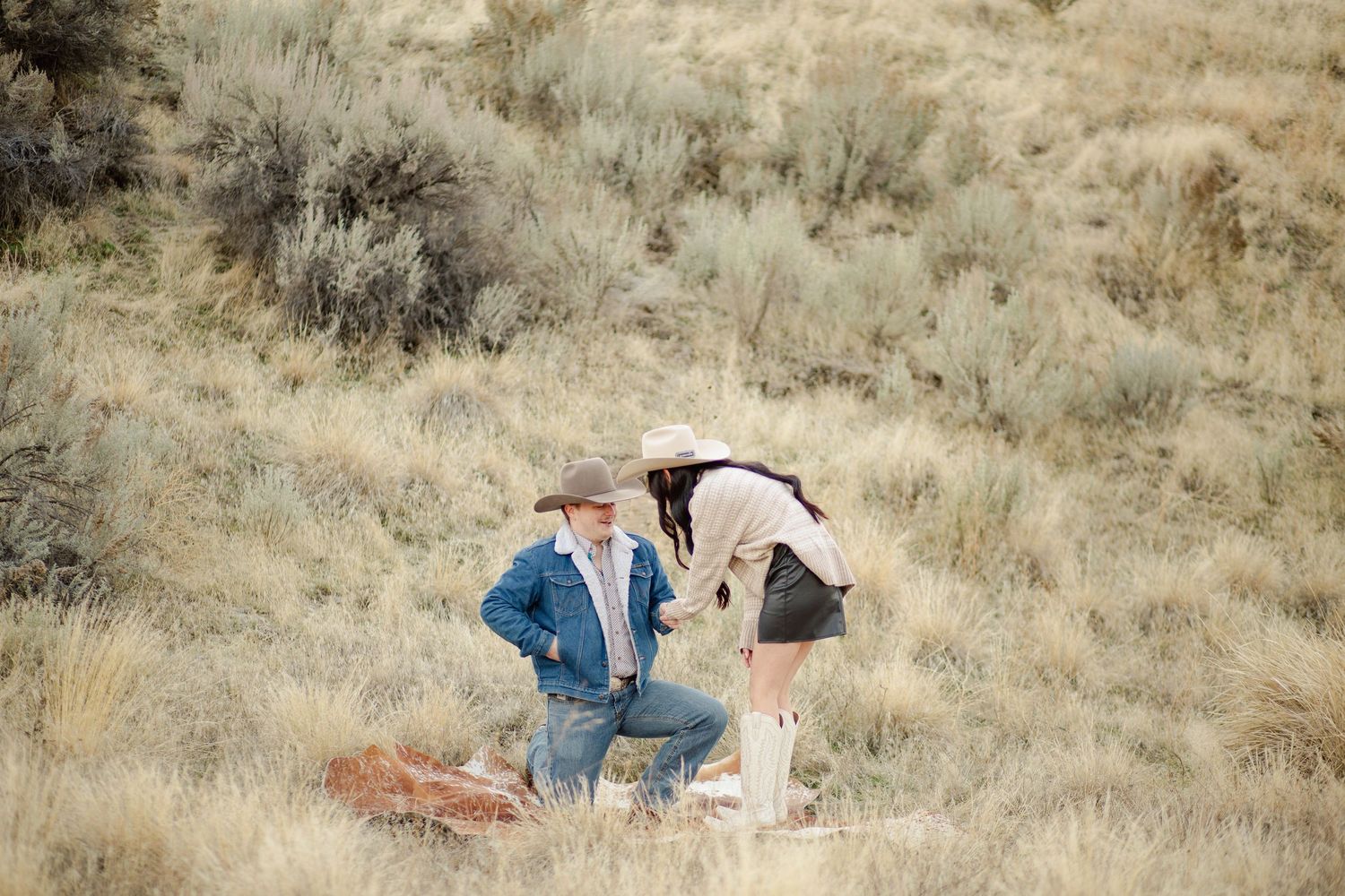 This warm photo shows a happy couple as they get engaged in the boise Idaho foothills showcasing the green sage brush taken by Stoked Media