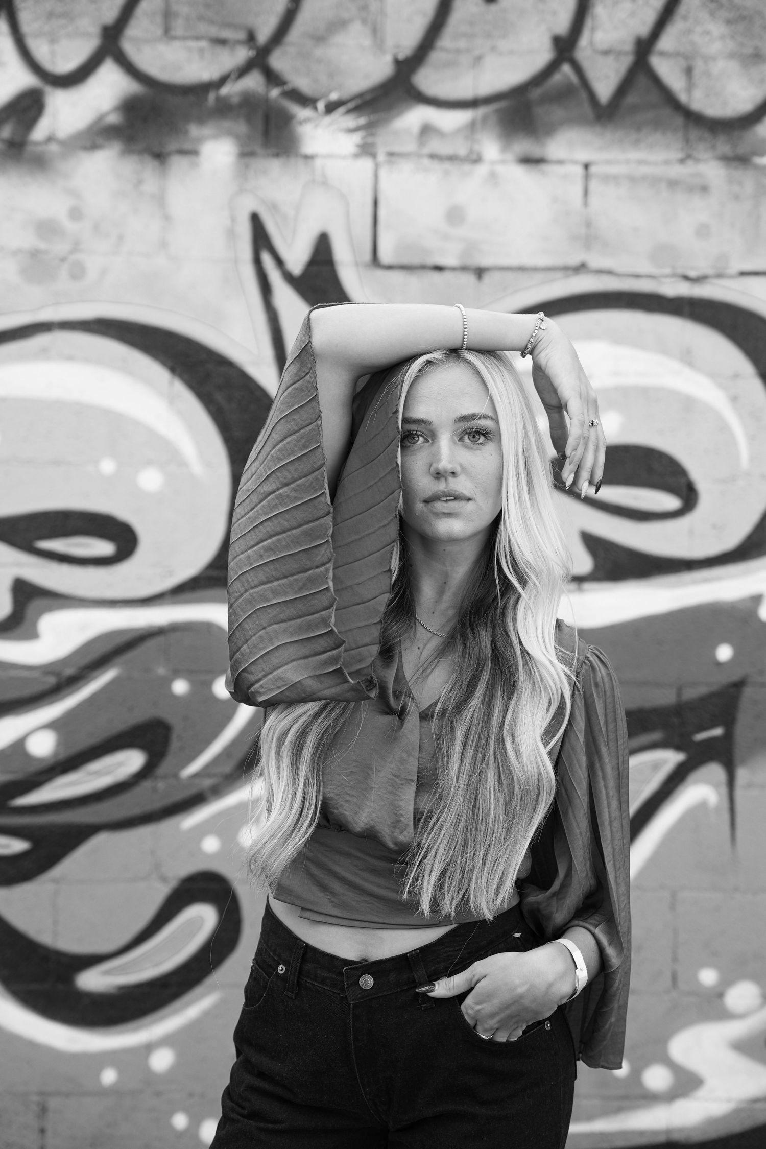 This playful photo shows a young blond modal wearing a flowing top as she poses whit her arm draped over her head in Salt Lake City Utah