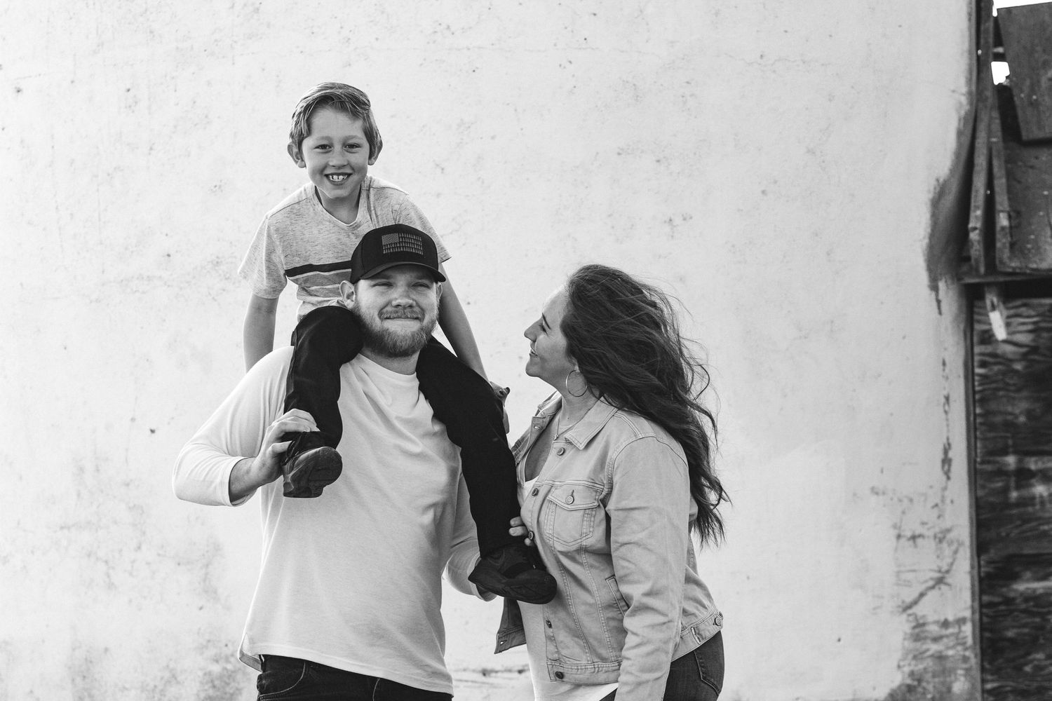This black and white photo shows a young family laughing and enjoying each other's company in the crisp fall air in eagle Idaho.
