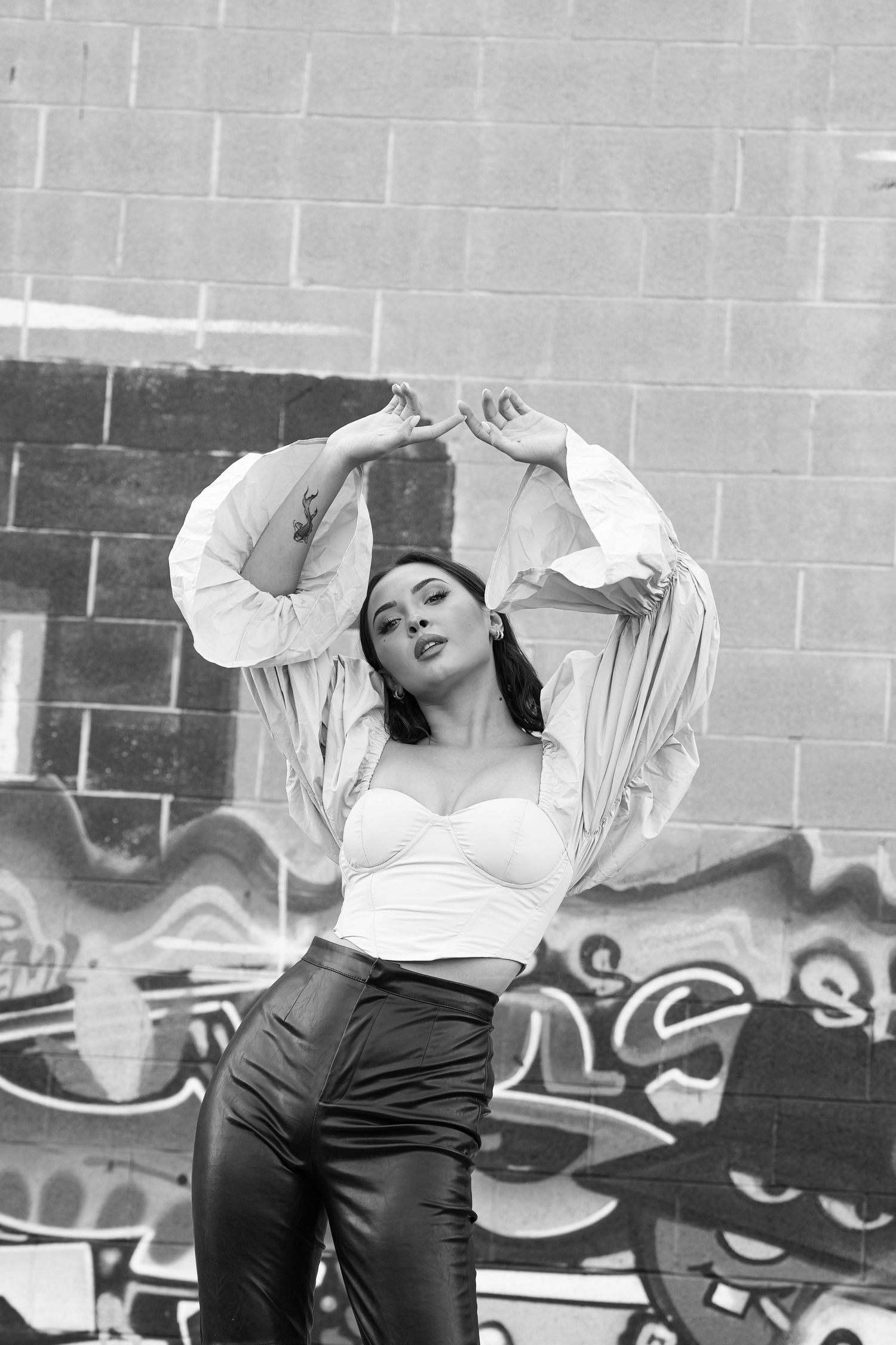 A black and white photo sequence shows a model in white top and dark pants performing expressive movements against a wall.