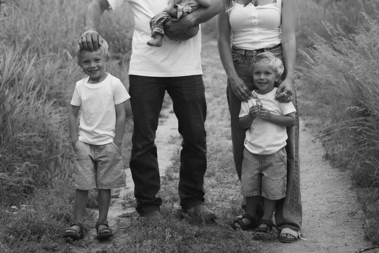 Black and white photo of two young boys standing with parents on a nature trail.