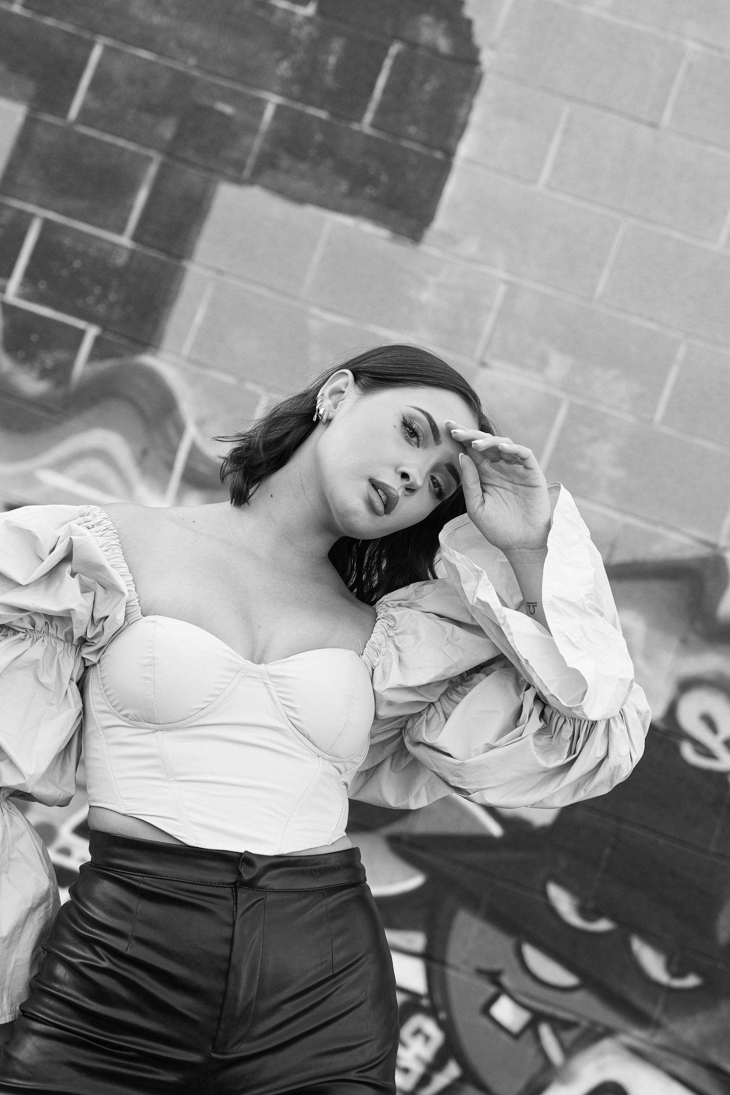 Angelic model with short black hair posses in graffiti ridden ally located in set lake city