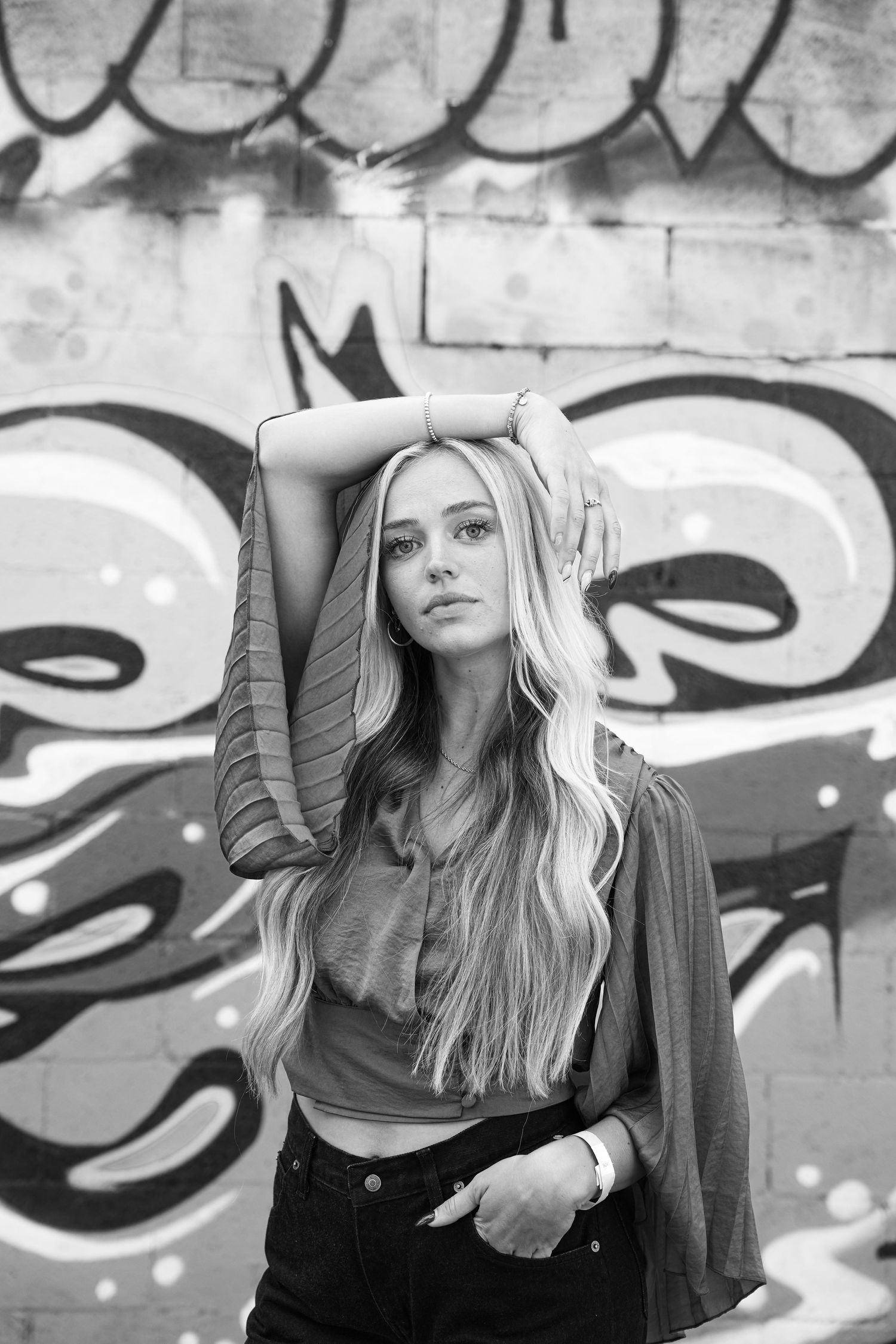 blond model wearing a flowing shirt posses against a graffiti covered wall in a ally in salt lake city