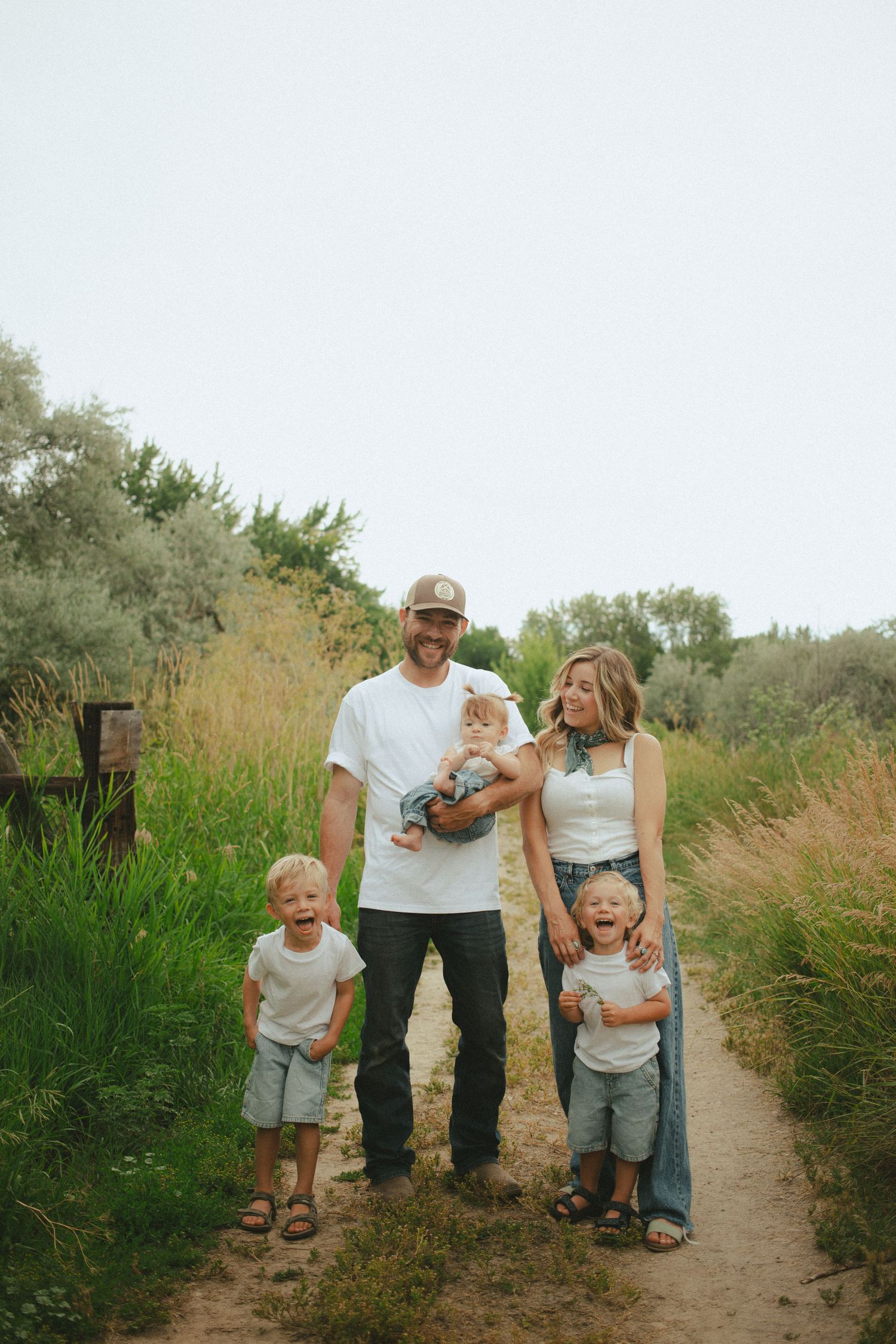 Joyful family of five laughs together on a scenic outdoor nature trail path.