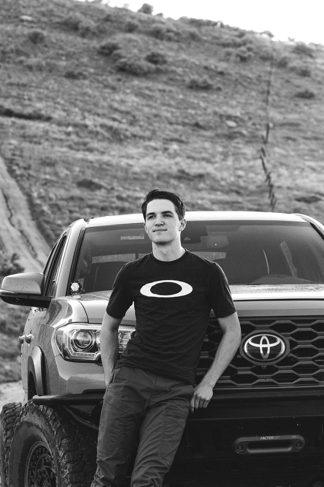 High school graduate leans against his truck while he gets his photos taken in the Boise foot hills in this black and white image
