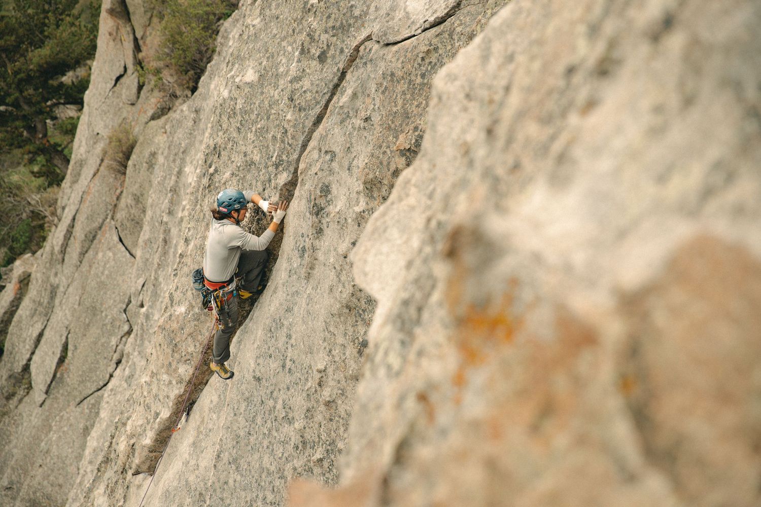 Rock climber scales a steep cliff face using technical climbing techniques and safety gear.
