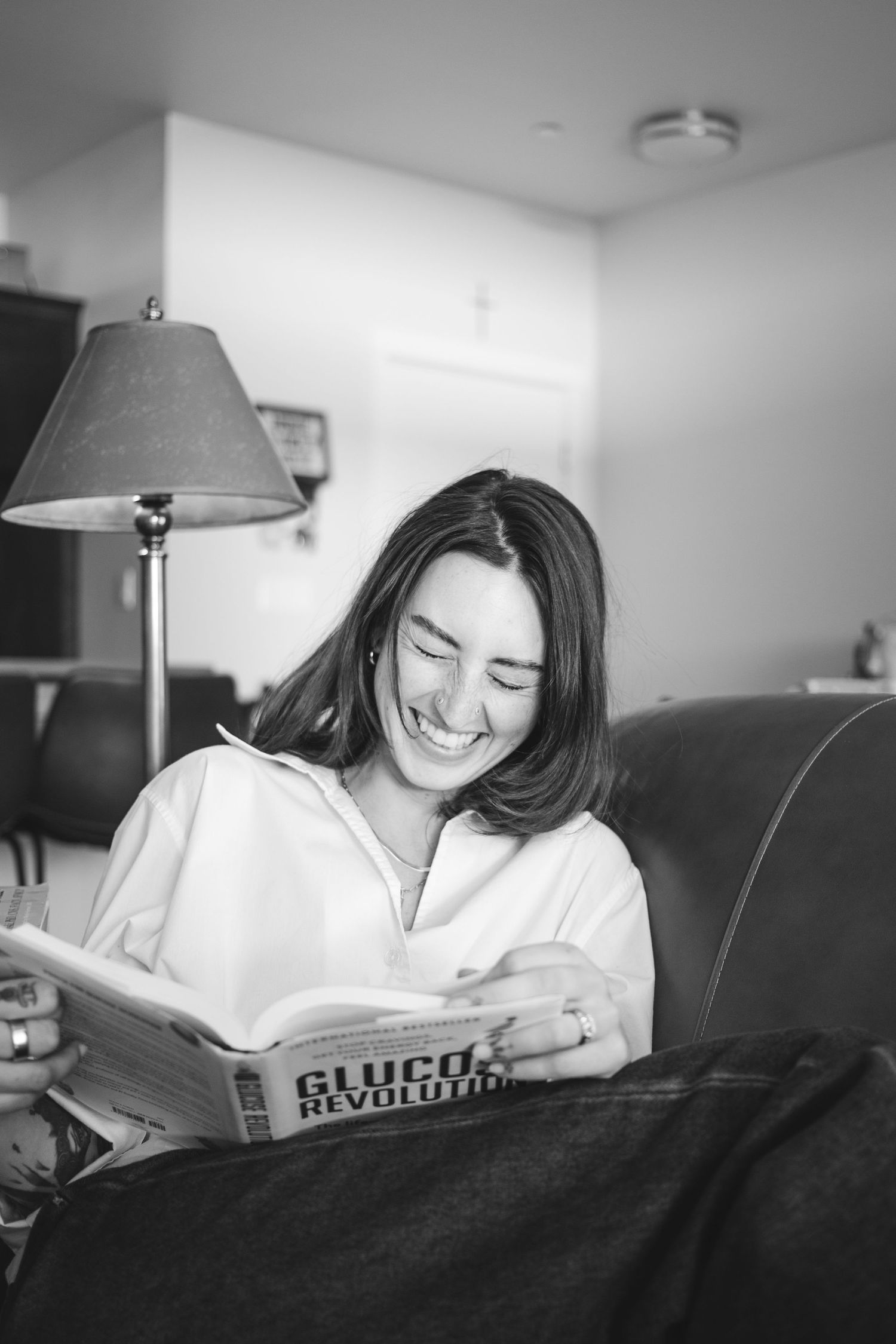 This black and white photo shows a girl laughing as she poses for a cozy portrait in her home based in Eagle Idaho