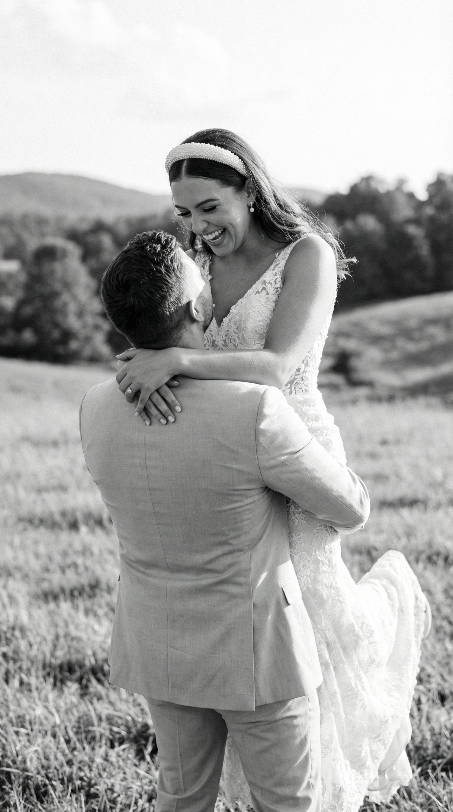 Joyful wedding couple embraces in a sun-lit field during their countryside celebration.Luxembourg wedding photographer