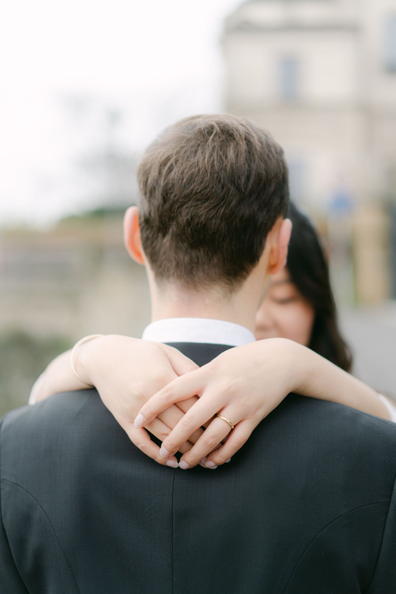 Close-up detail of hands resting on a black suit jacket showing a wedding ring.Luxembourg wedding photographer