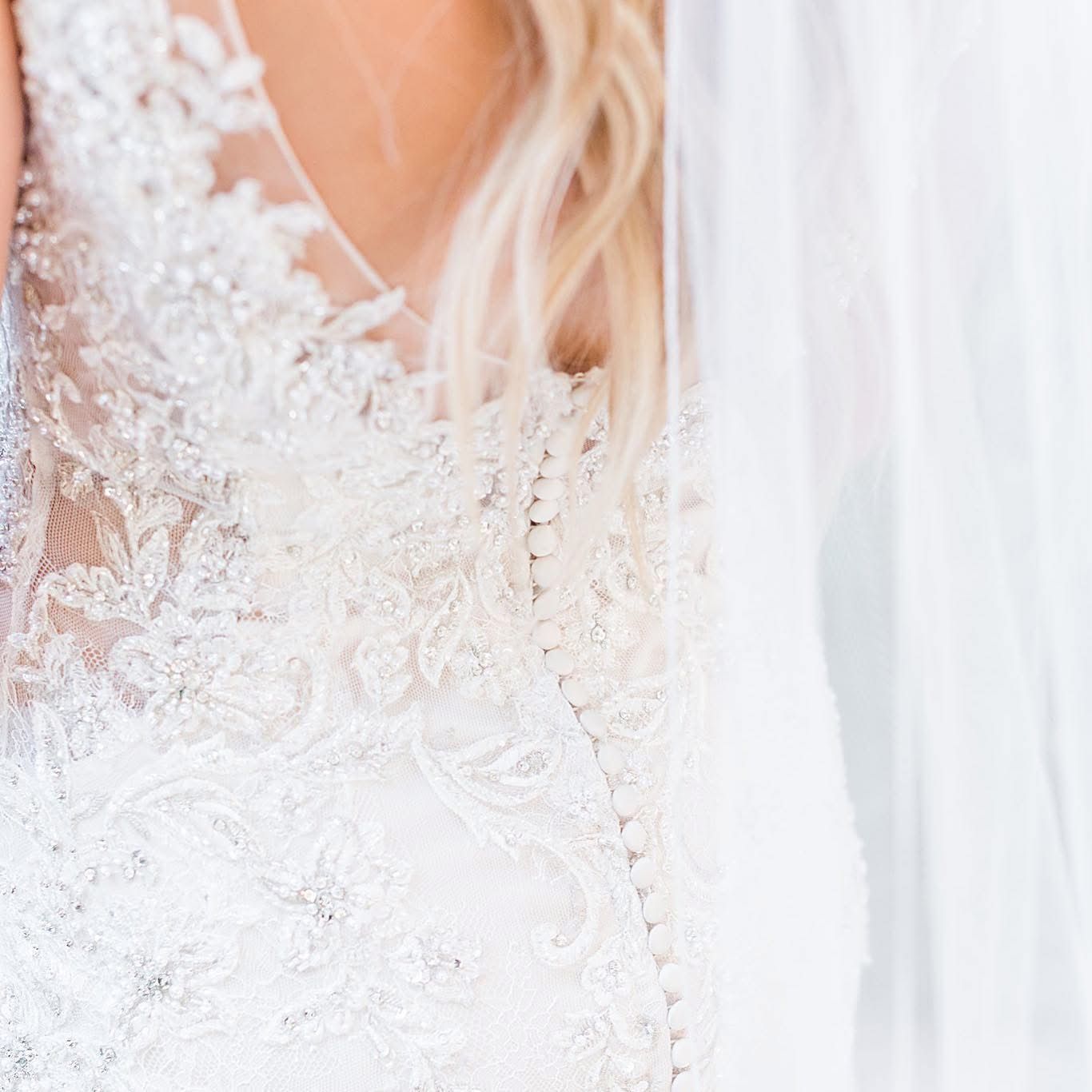 Detailed shot of intricate white lace pattern on wedding dress bodice.