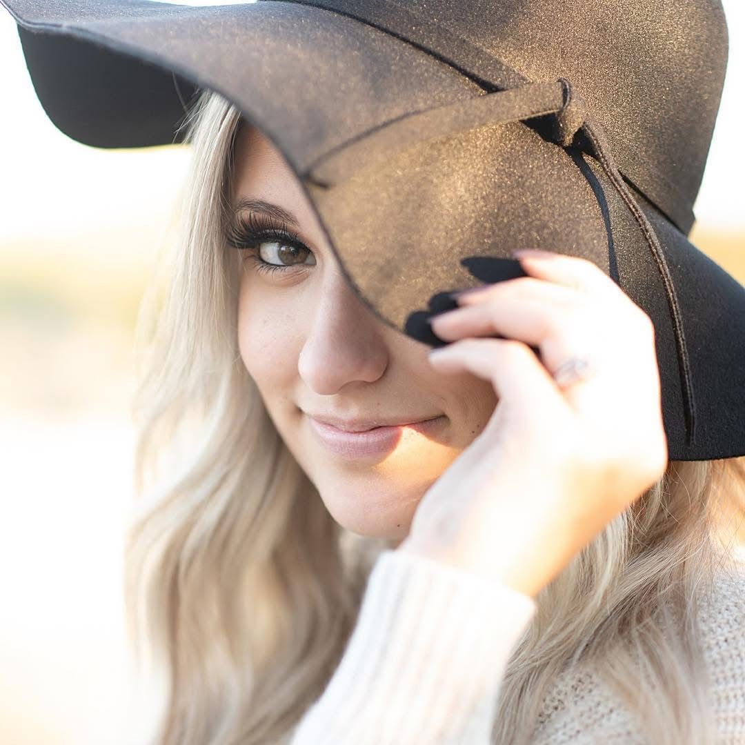 Stylish portrait shot featuring a wide-brimmed hat and blonde waves in warm sunlight.