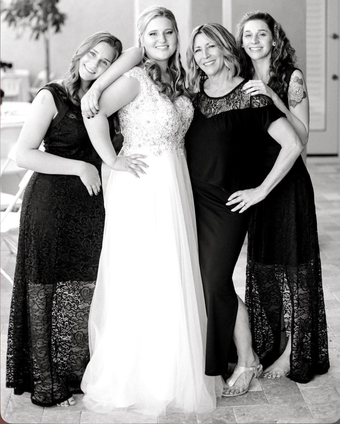 Wedding party poses together with bride in white gown and bridesmaids in elegant black dresses.