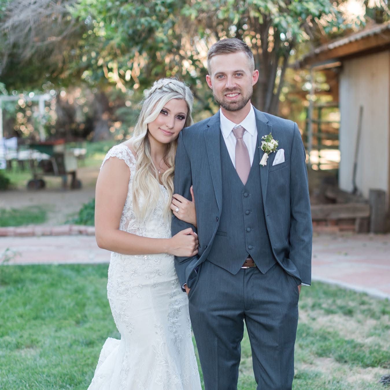 Elegant wedding portrait of newlyweds in formal attire on a garden patio.