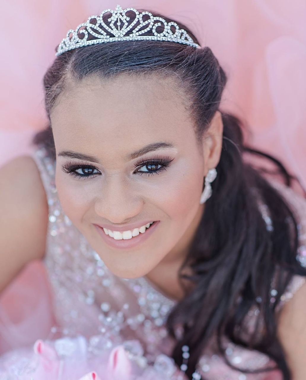 Beautiful bridal portrait featuring a delicate silver tiara and soft pink background.