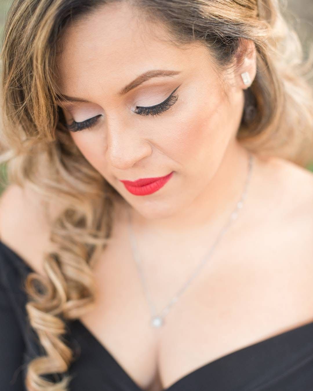 Close-up beauty portrait showcasing glamorous makeup with winged eyeliner and red lipstick.