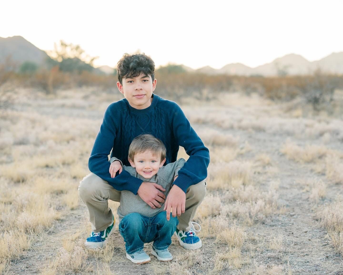 Father and child portrait in desert landscape with mountains in background.