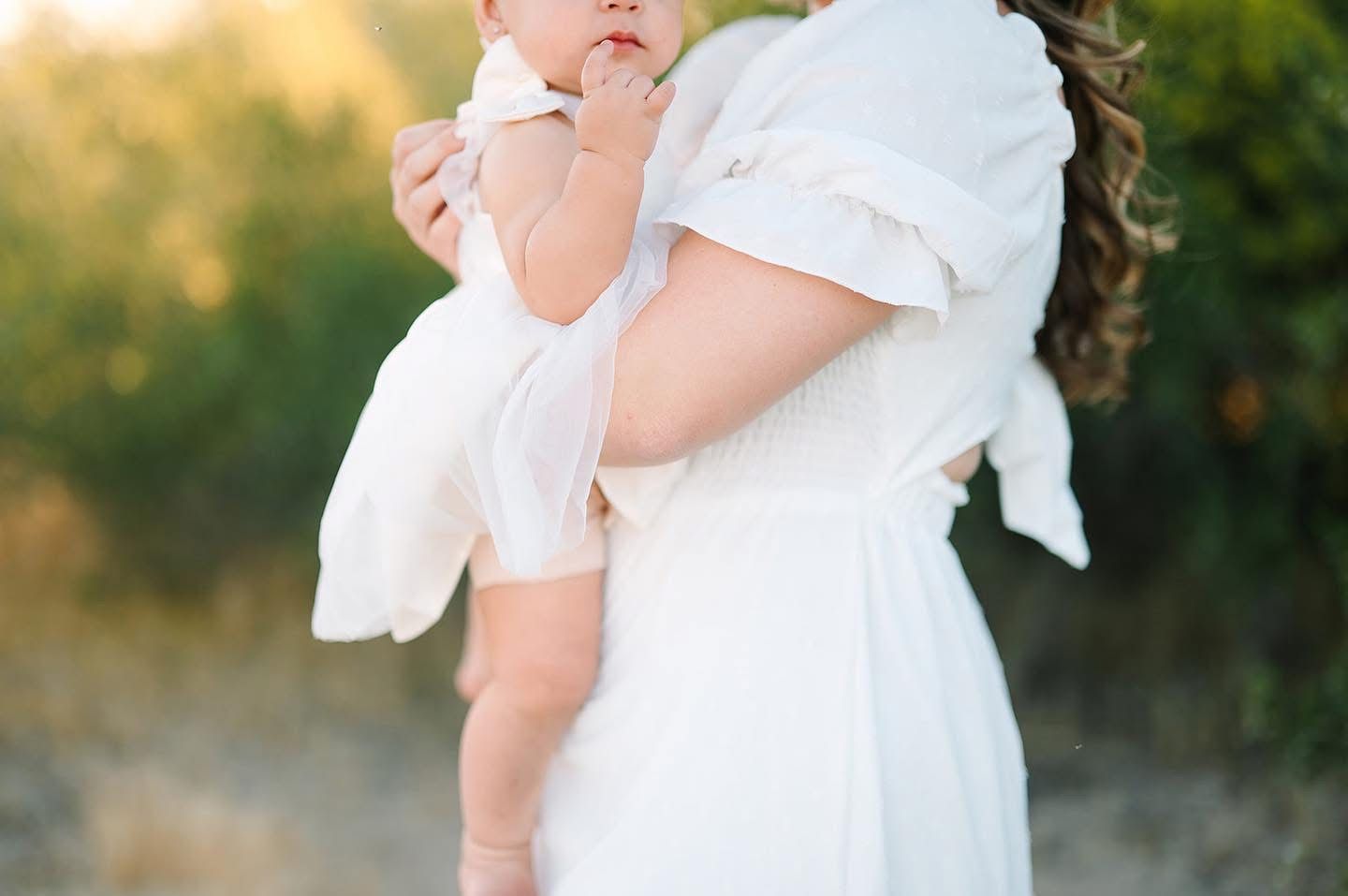 Ethereal side view of flowing white dress details against golden sunset light.