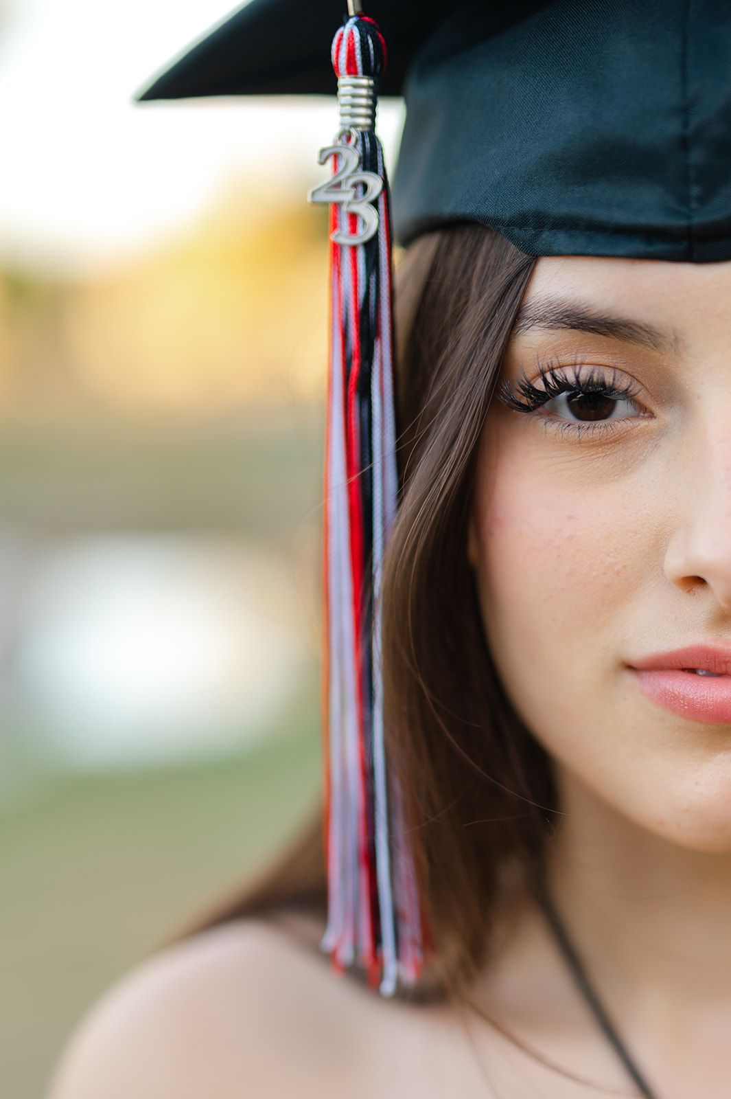 Close-up of graduation tassel with red and blue colors against blurred background.
