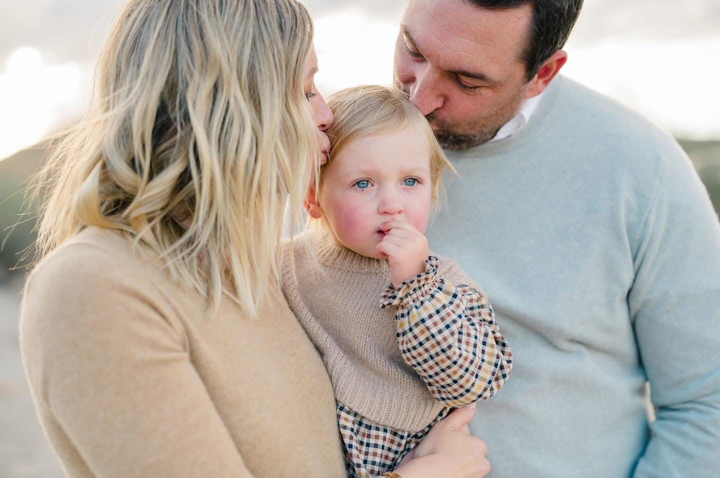 Sweet family moment captured in soft neutral tones against light background.