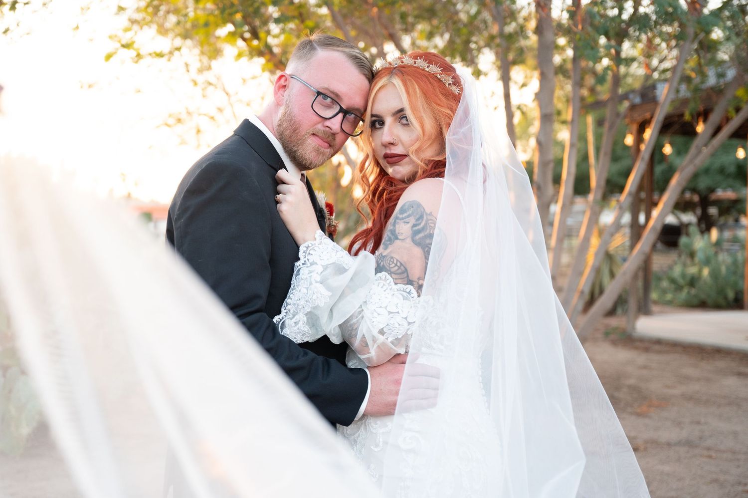 A romantic wedding portrait at sunset with a long white veil flowing in the soft golden light.