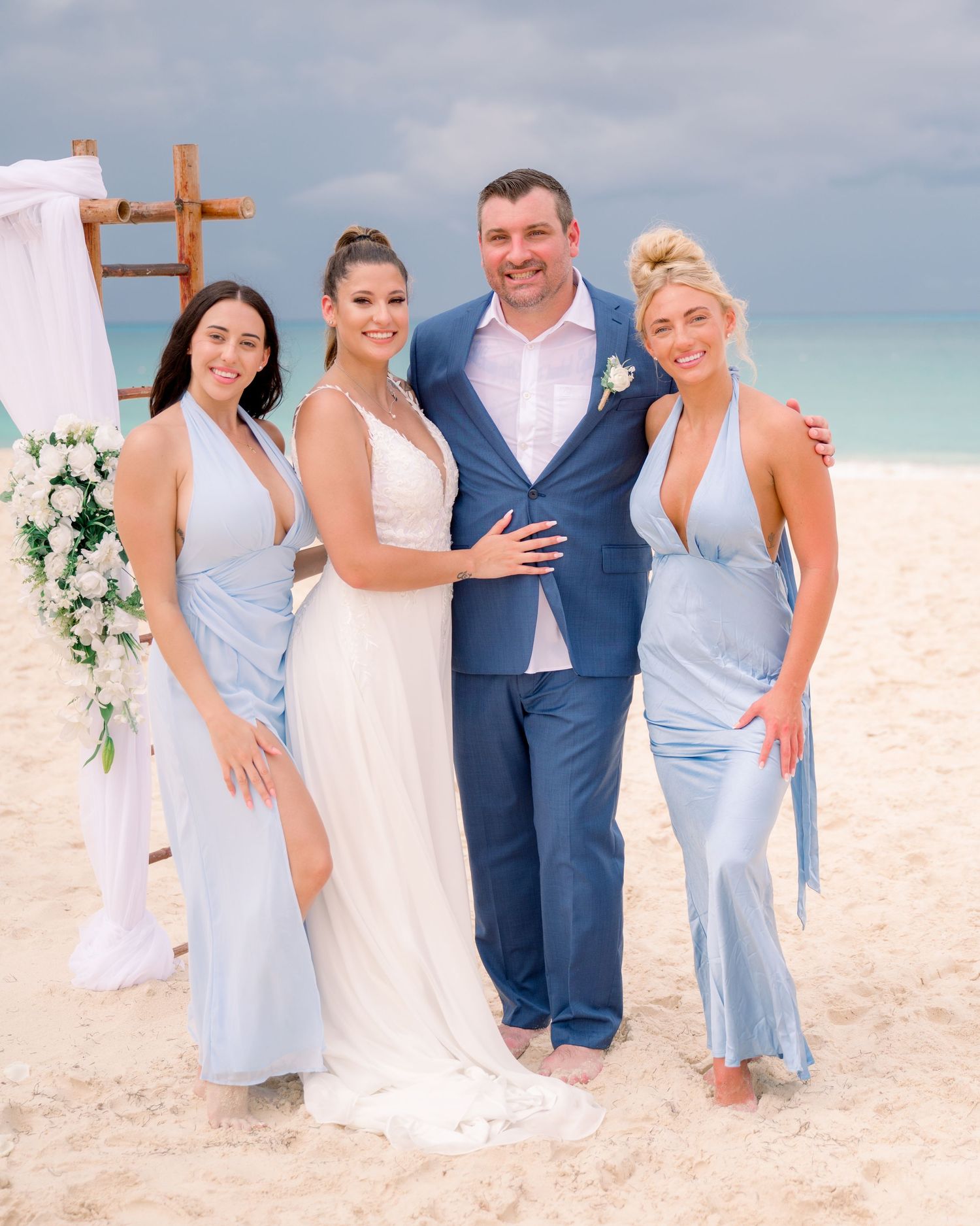 A beachside wedding ceremony setup with a wooden cross arch and floral arrangements.