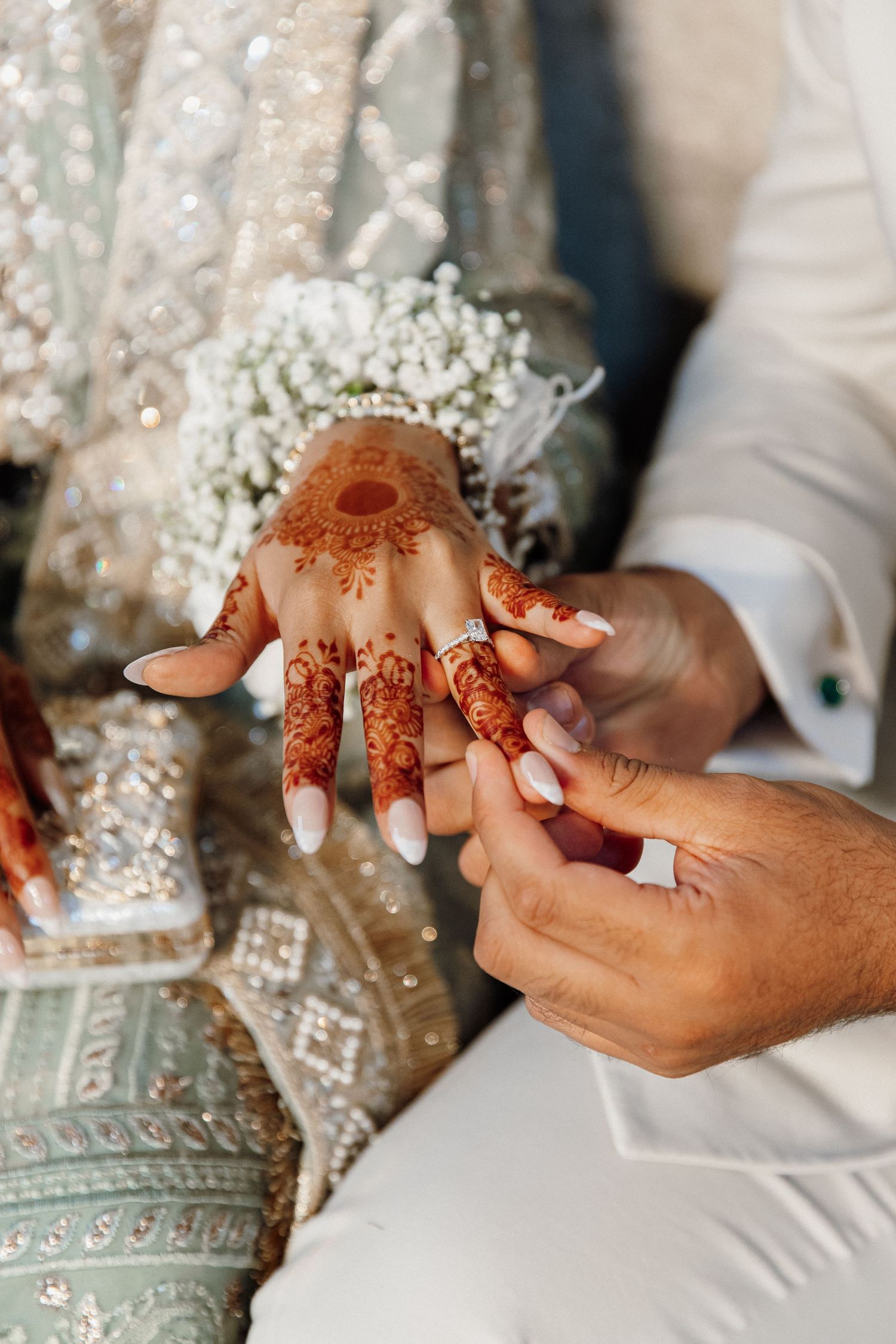 Close-up of hands during traditional mehndi ceremony with intricate henna designs.