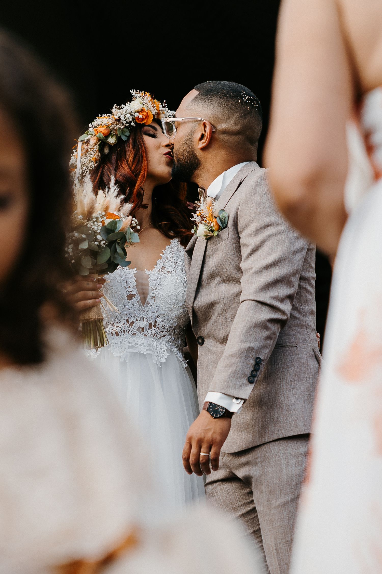 Newlyweds share an intimate moment wearing floral crown and gray suit.