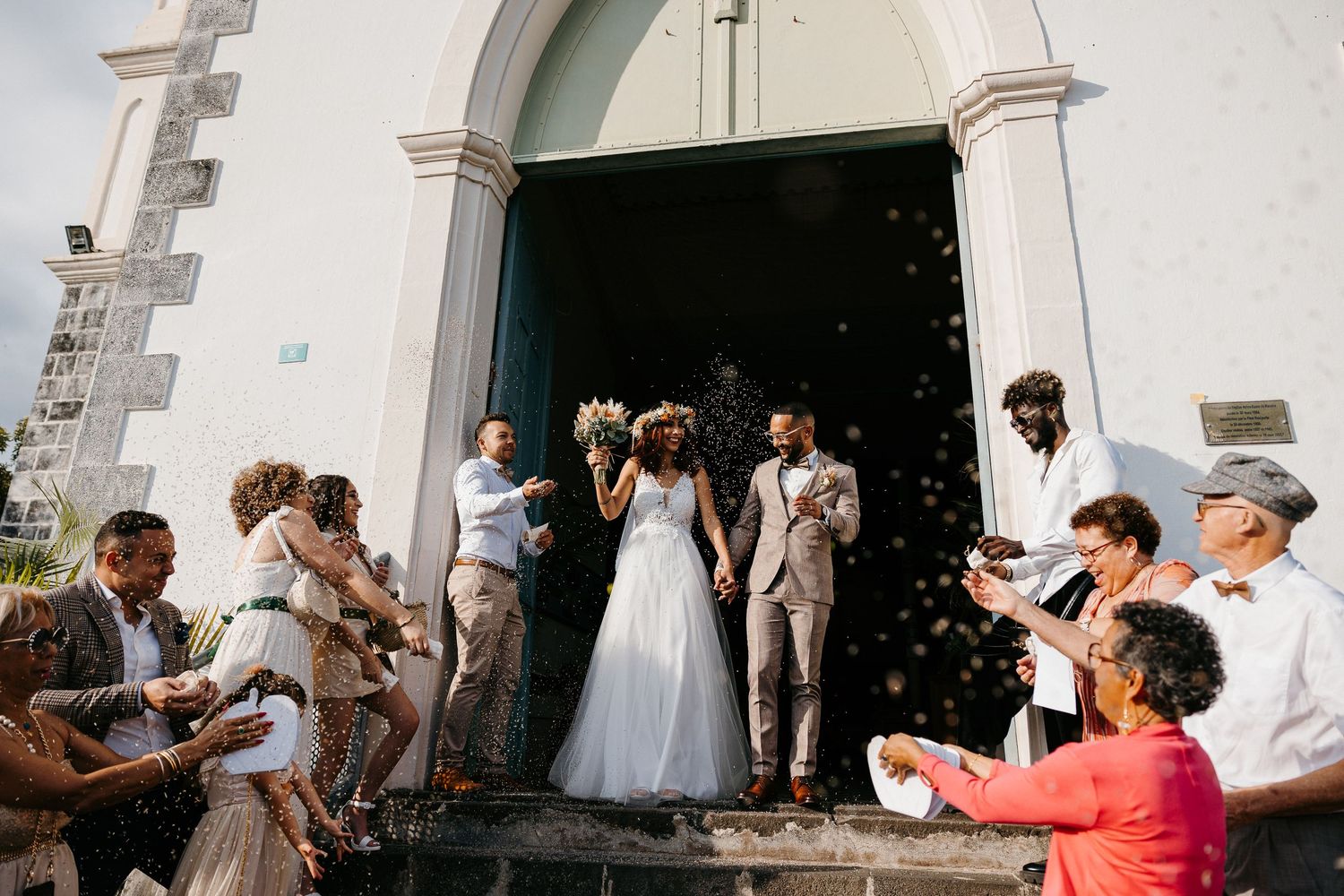Wedding guests shower newlyweds with confetti on church steps.