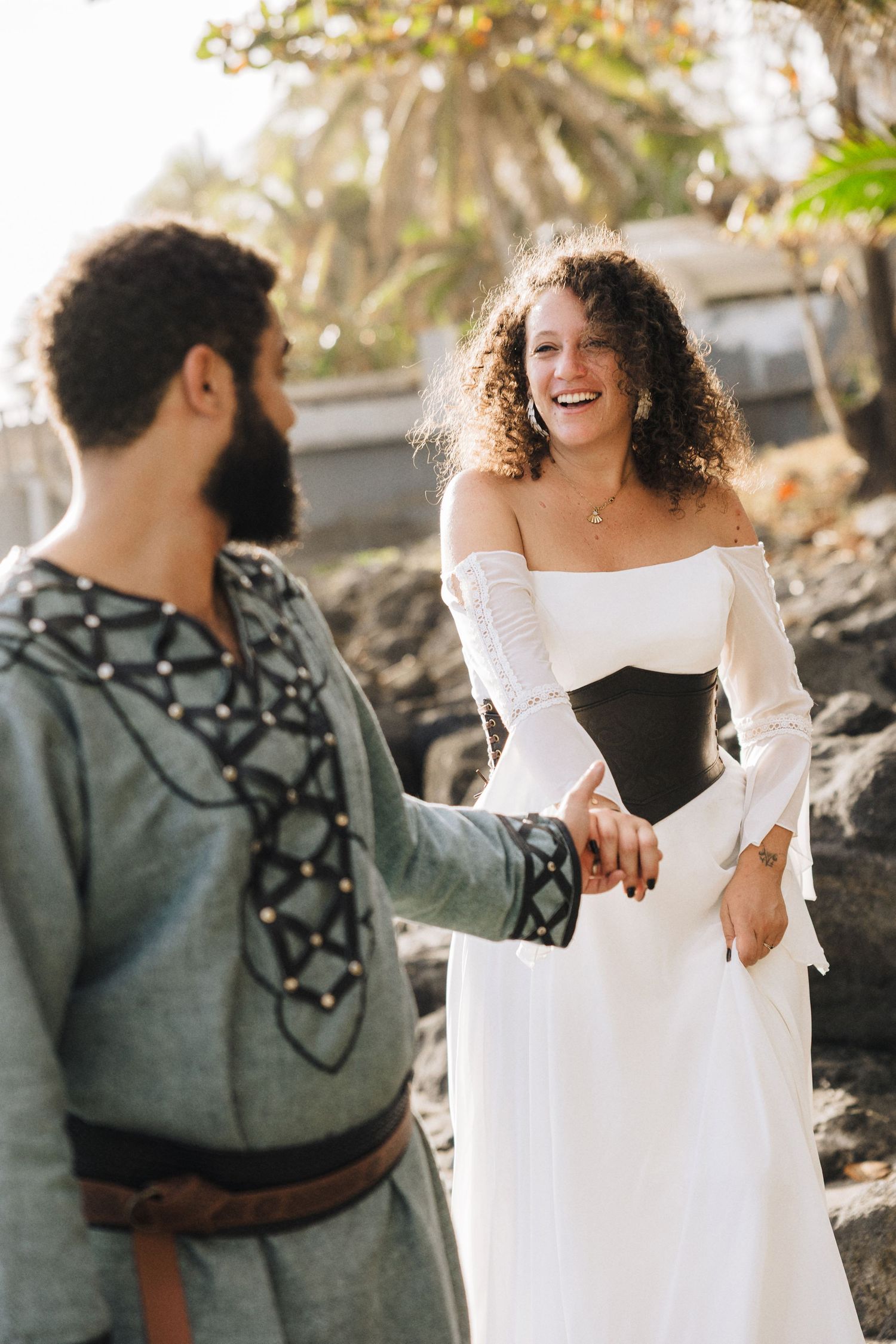 Couple in contrasting outfits share joyful moment outdoors, with one in white dress.