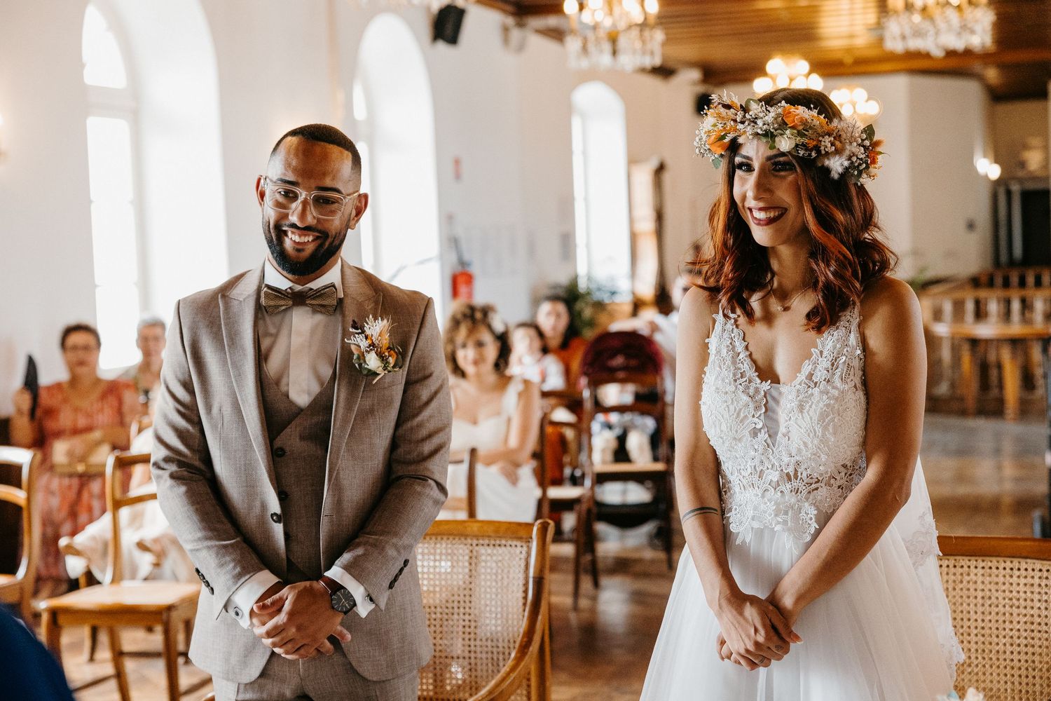 Wedding ceremony in a bright church with elegant chandeliers and arched windows.
