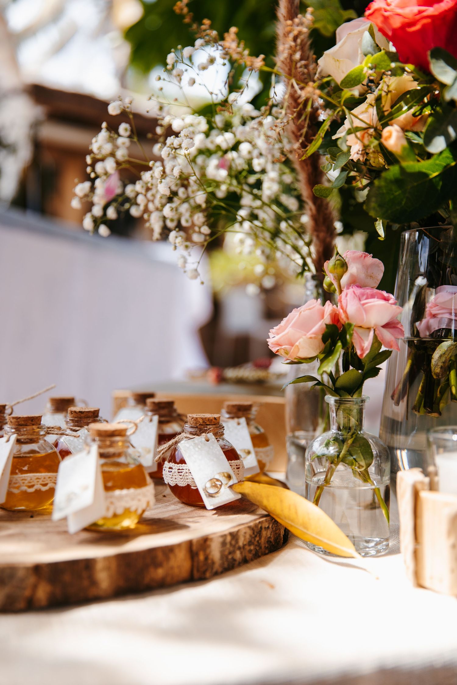 Wedding reception table with honey favors, pink flowers, and rustic wooden decor.