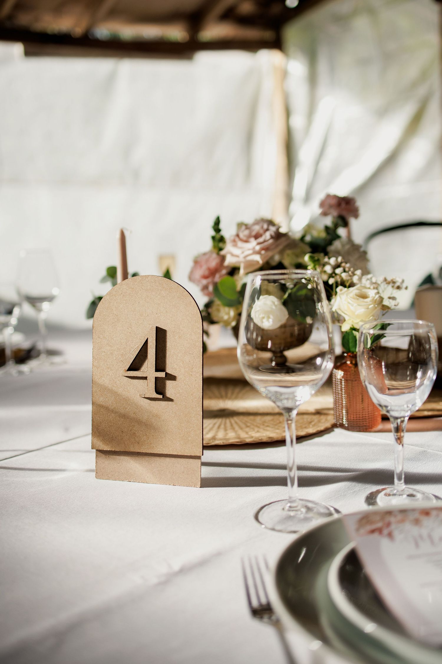 Close-up of wedding table place settings with wine glasses and kraft paper name cards.