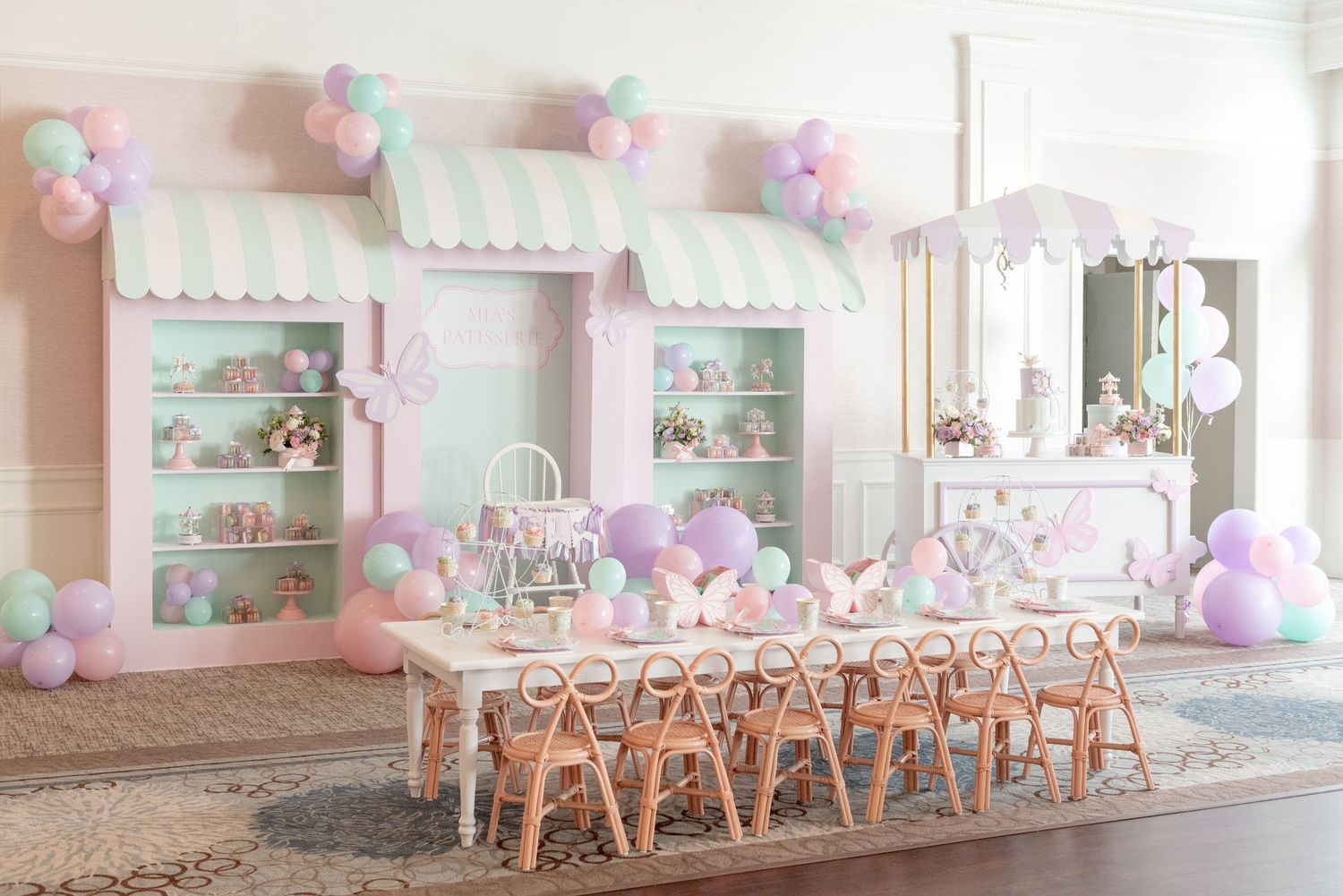 Pastel pink and mint event space decorated with balloons and white chairs for a celebration.