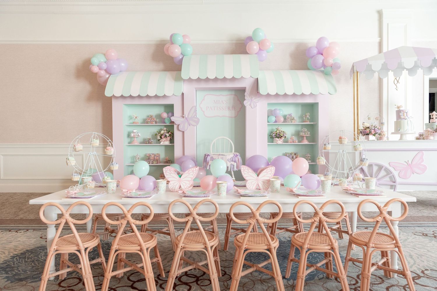 Pink and mint green party decorations adorn a table setting with director chairs and floral centerpieces.