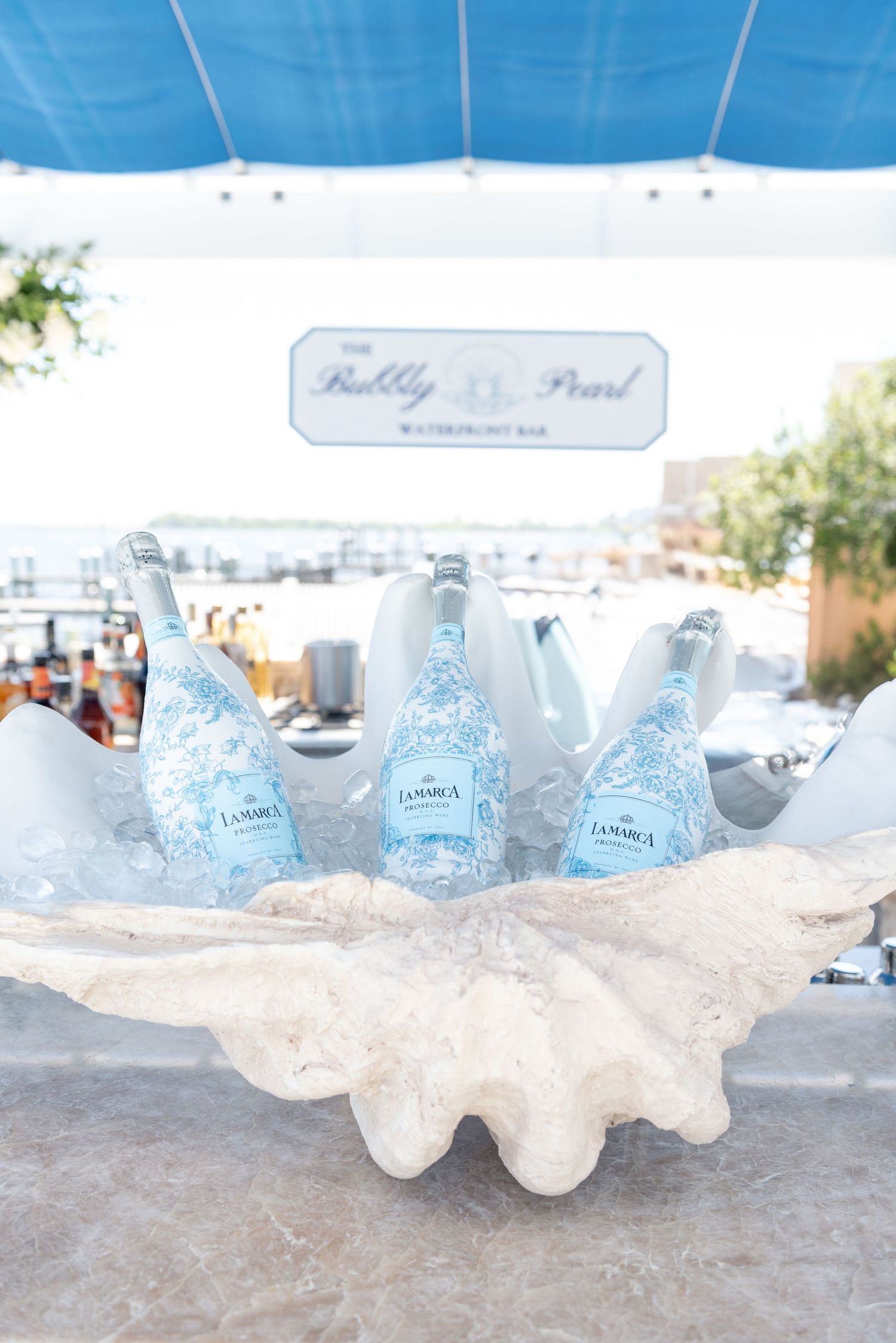 Glass bottles of clear water chilling in crushed ice at an outdoor event display.