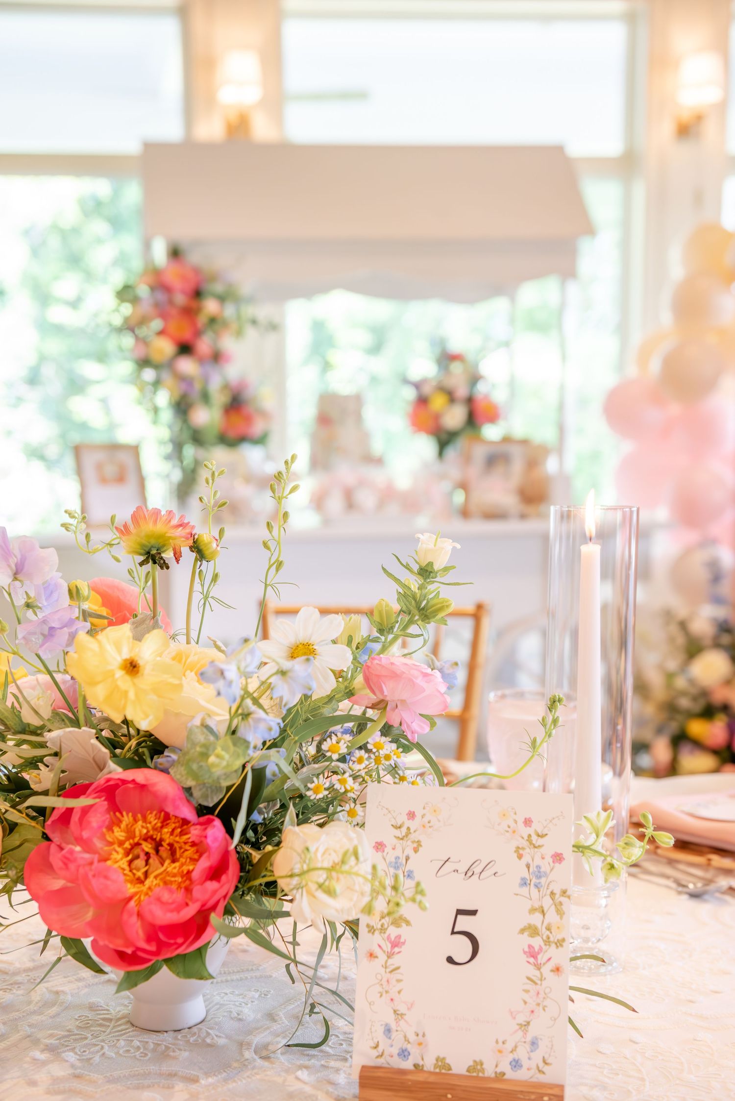 Elegant bridal shower table settings with coral and peach floral centerpieces and delicate table number holders.
