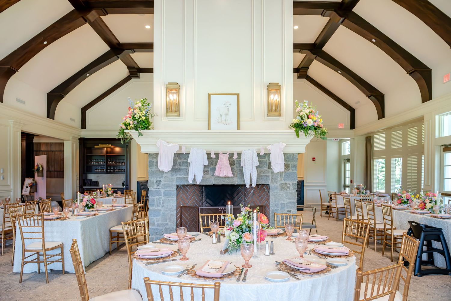 Elegant bridal shower venue with exposed wooden beams, white walls and round tables set for dining.