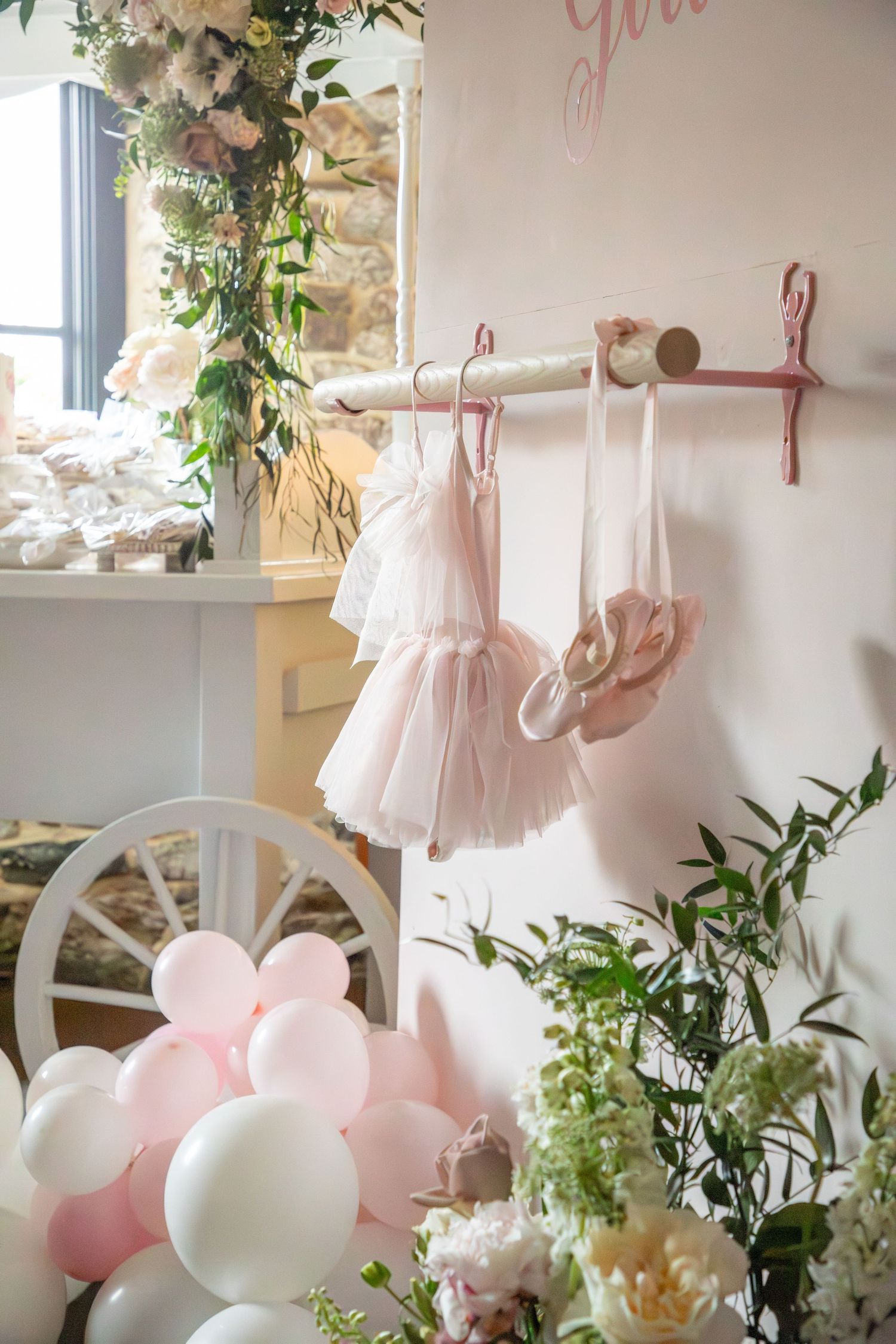 Pink and white balloons with delicate tulle decorations and greenery create an ethereal party atmosphere.