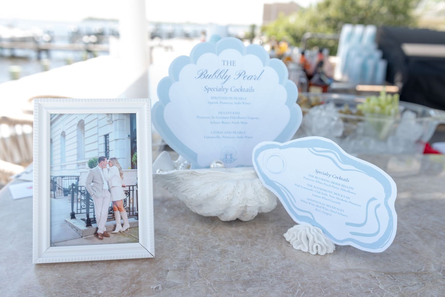Custom specialty cocktail menus with blue watercolor details and elegant calligraphy displayed on a light surface.