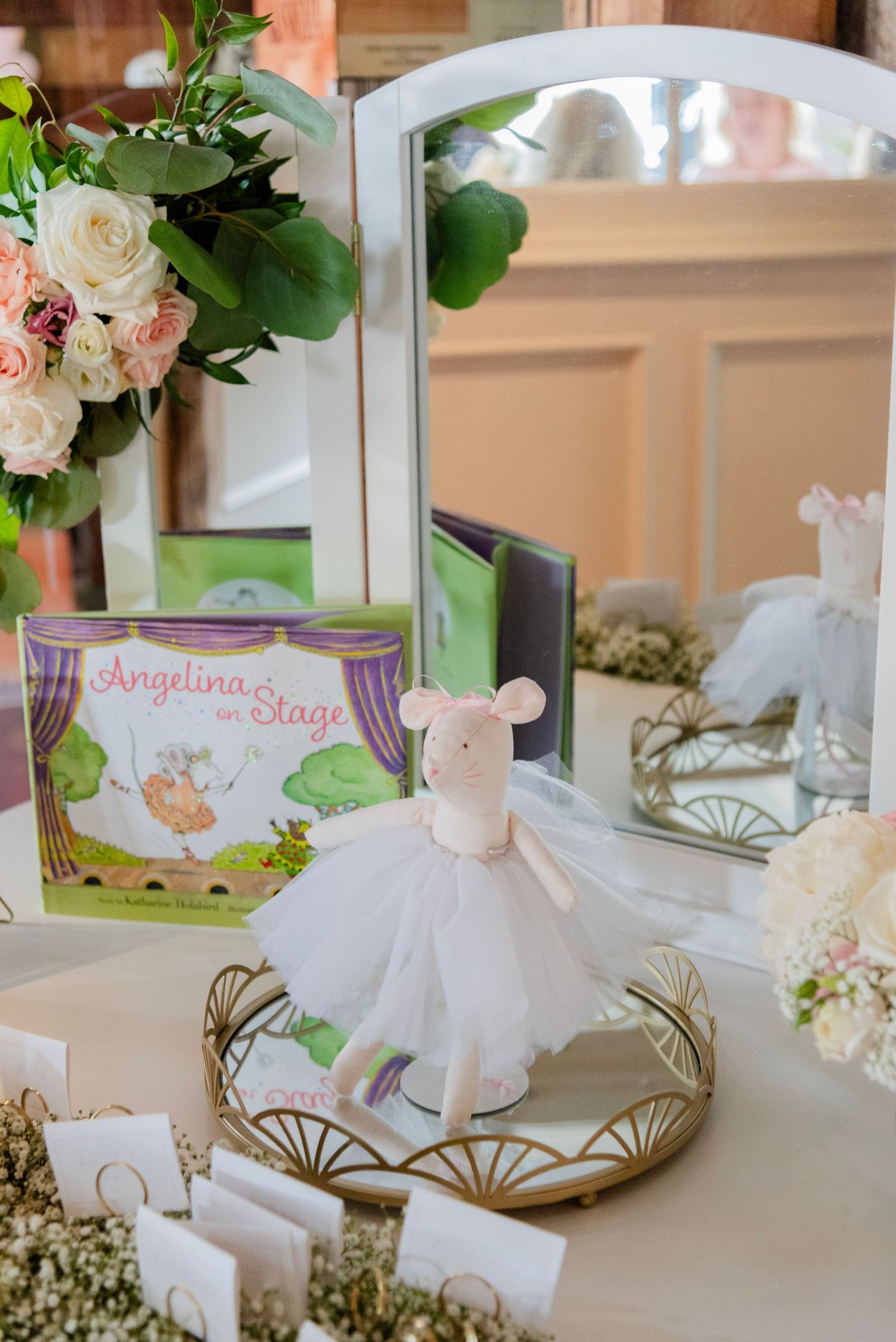 Elegant white ballet tutu decoration with floral arrangements and a children's storybook on a mirrored vanity display.